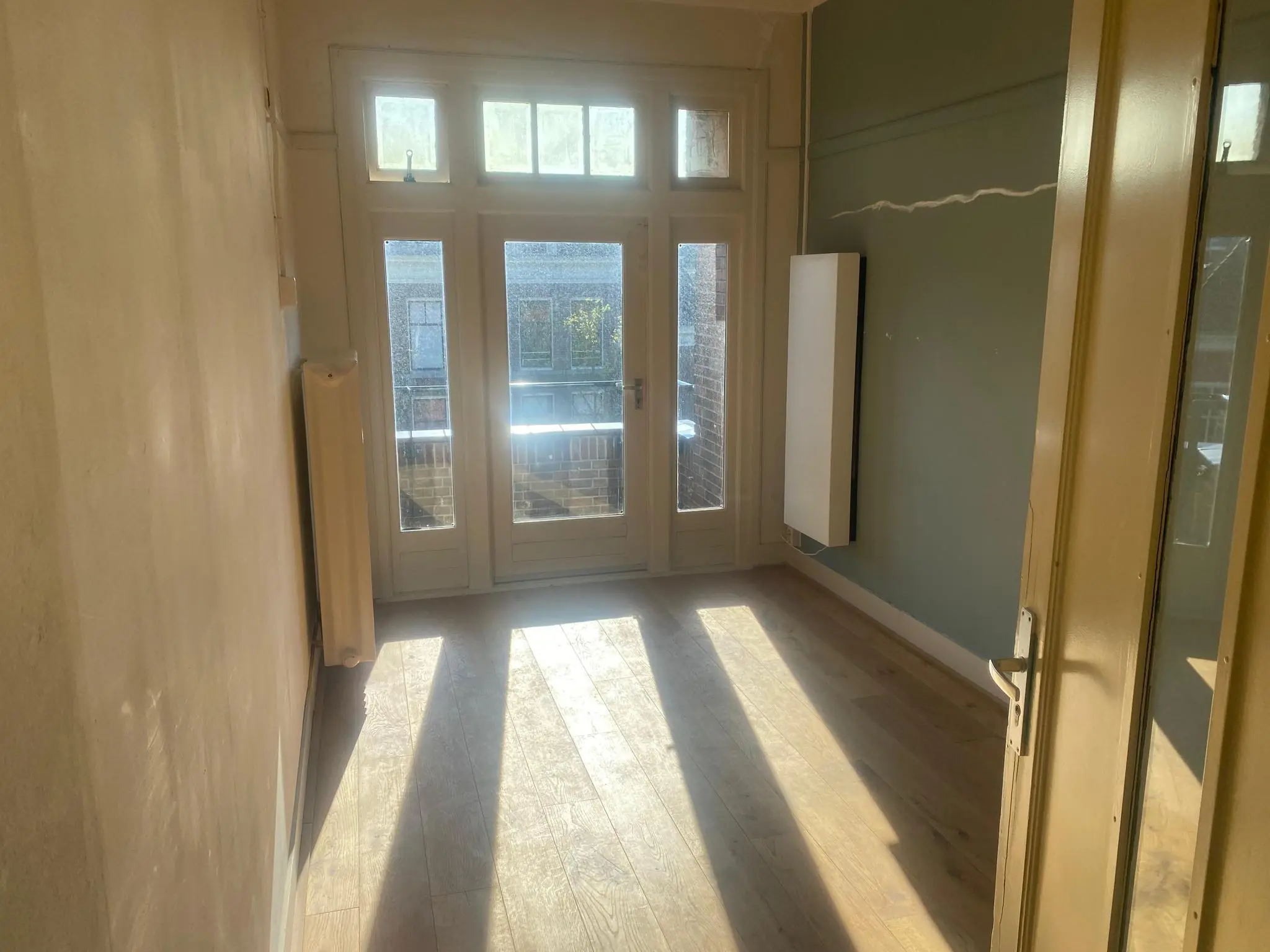 Lichte kamer met houten vloer en openslaande deuren naar een balkon aan de Gasthuisplaats.