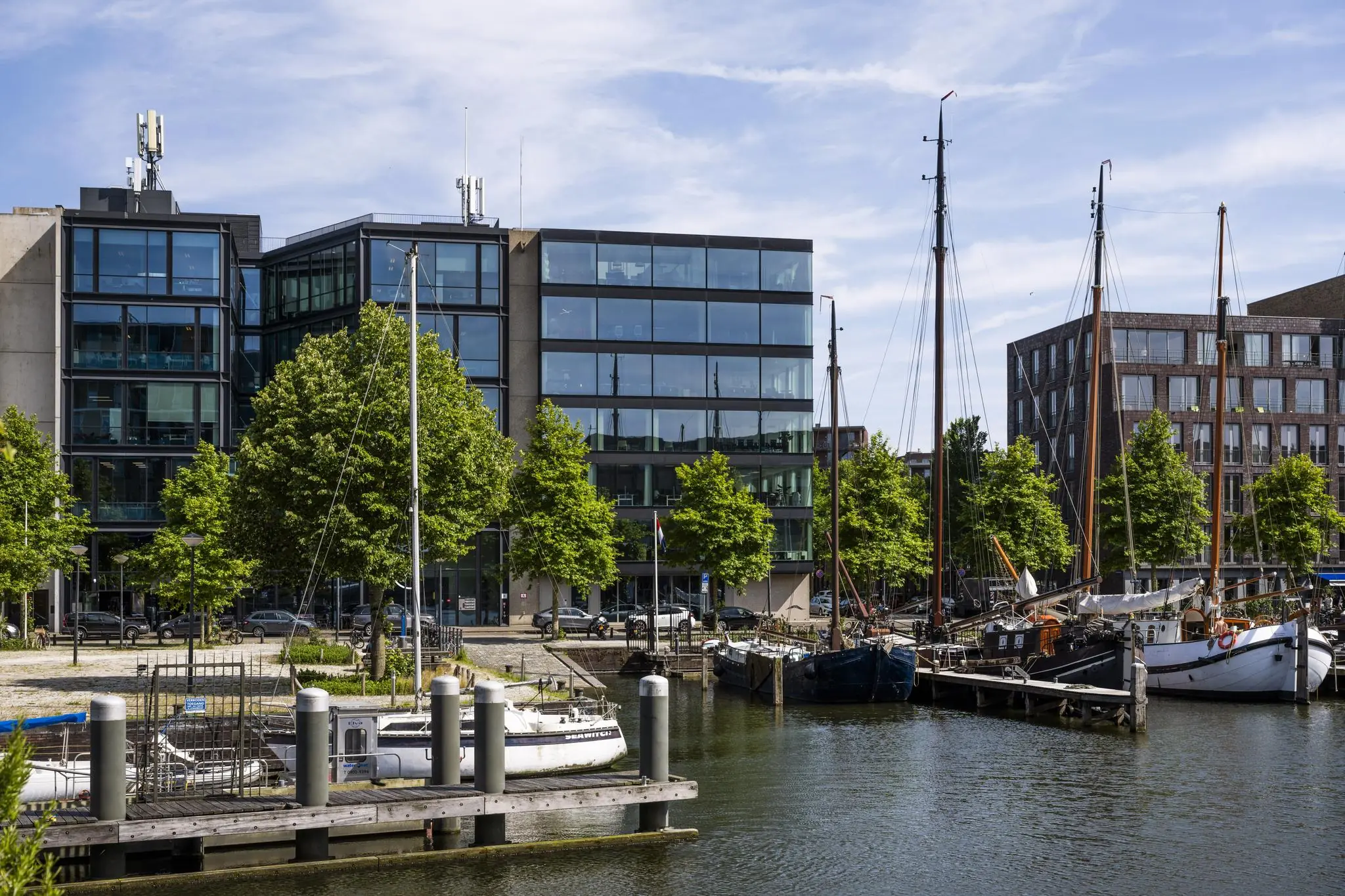 Moderne gebouw aan de Krijn Taconiskade met aangemeerde zeilboten in een rustige haven.