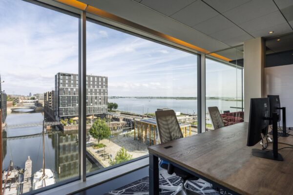 Kantoorruimte met uitzicht op de Krijn Taconiskade, moderne gebouwen en het IJmeer.