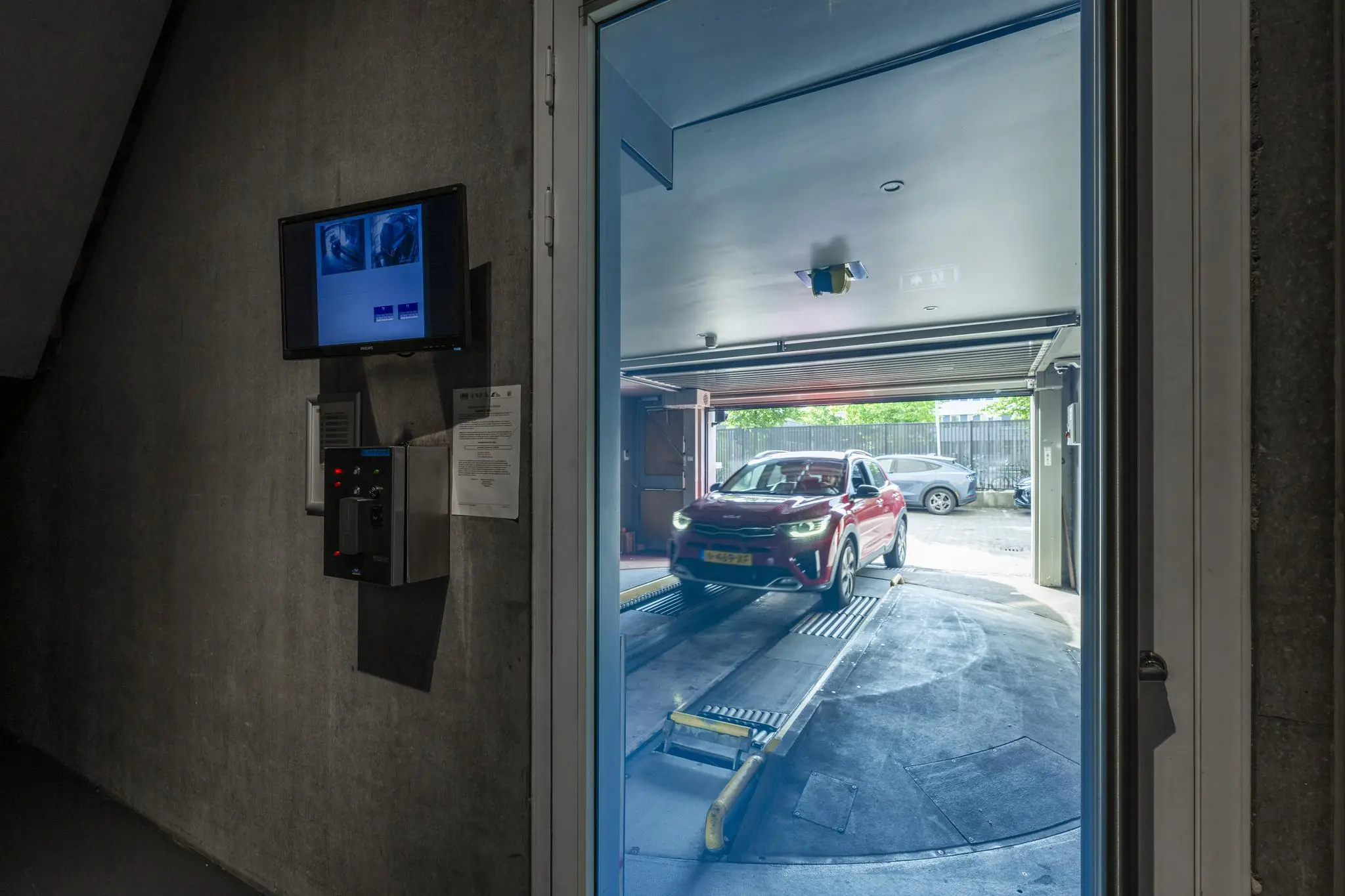 Een rode auto rijdt een geautomatiseerde parkeergarage binnen aan de Krijn Taconiskade.