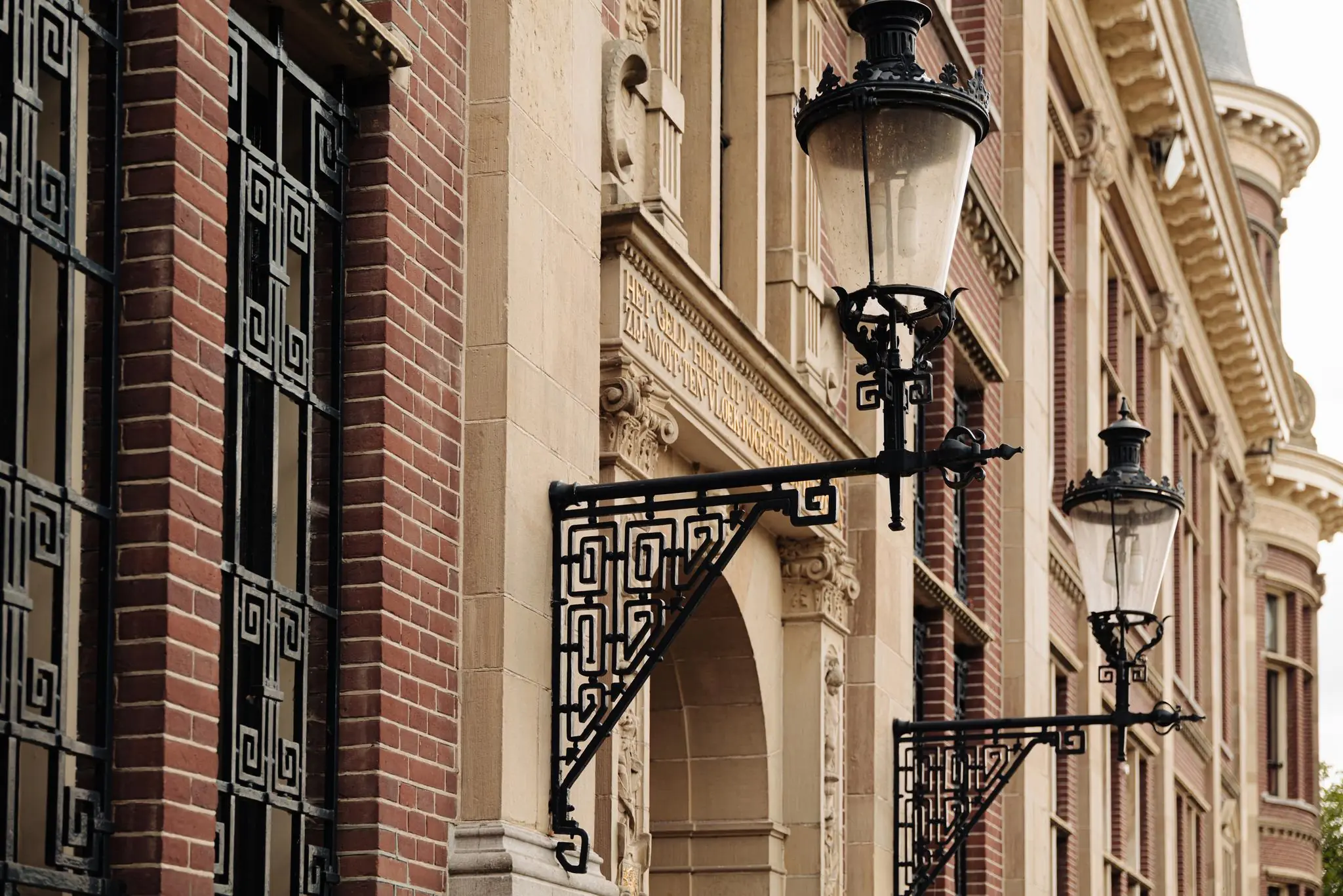 Gevel van een historisch gebouw aan de Leidseweg met sierlijke lantaarns en decoratieve smeedijzeren details.