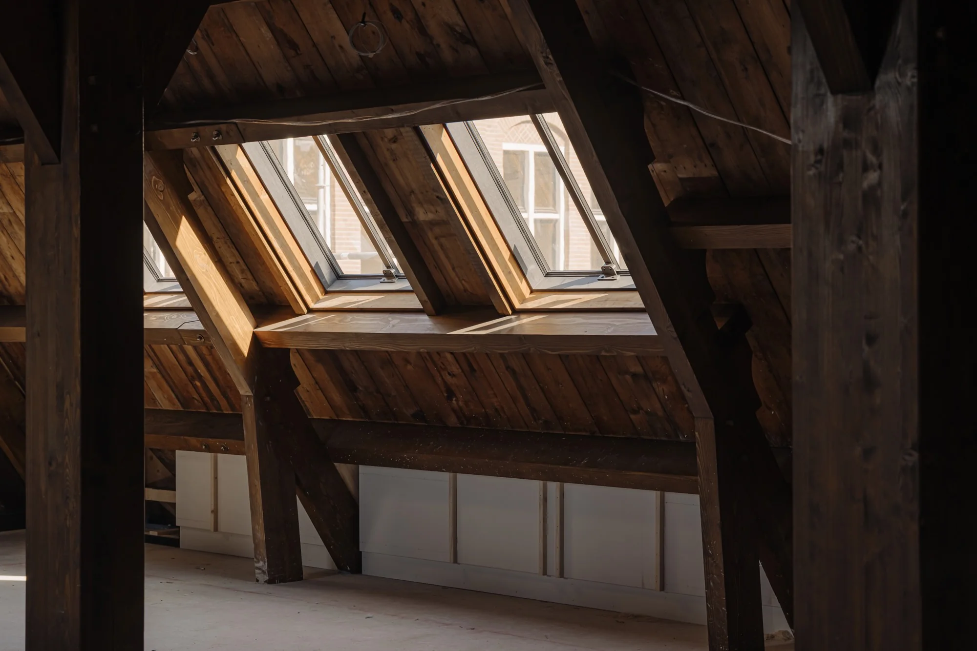 Zolderruimte met houten balken en meerdere dakramen aan de Leidseweg.