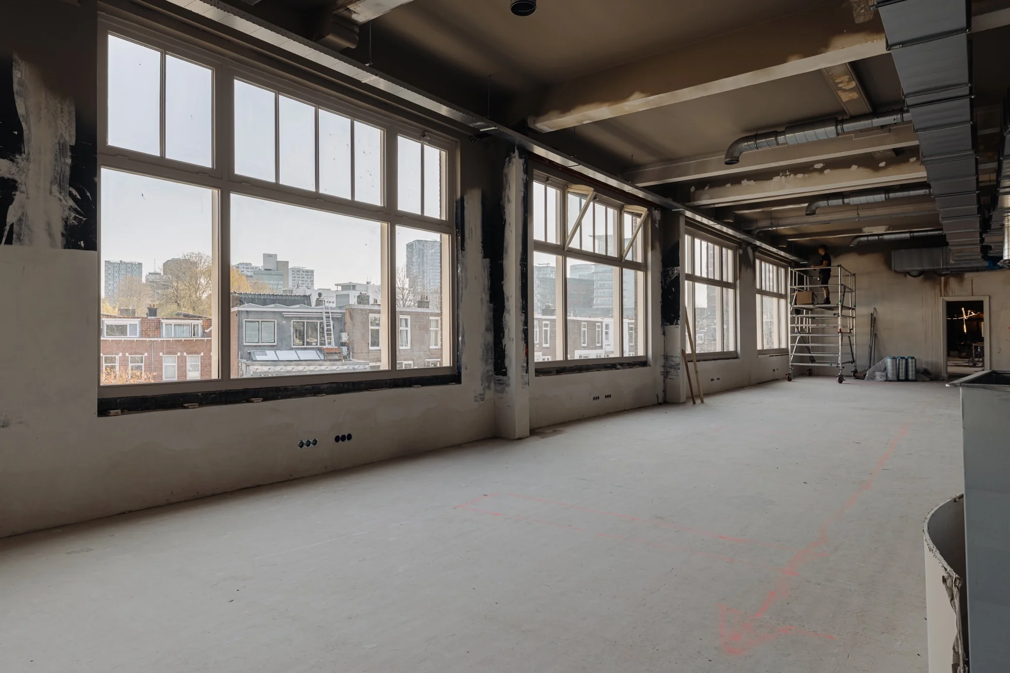 Leegstaand kantoor aan de Leidseweg in renovatie met grote ramen en uitzicht op de stad.