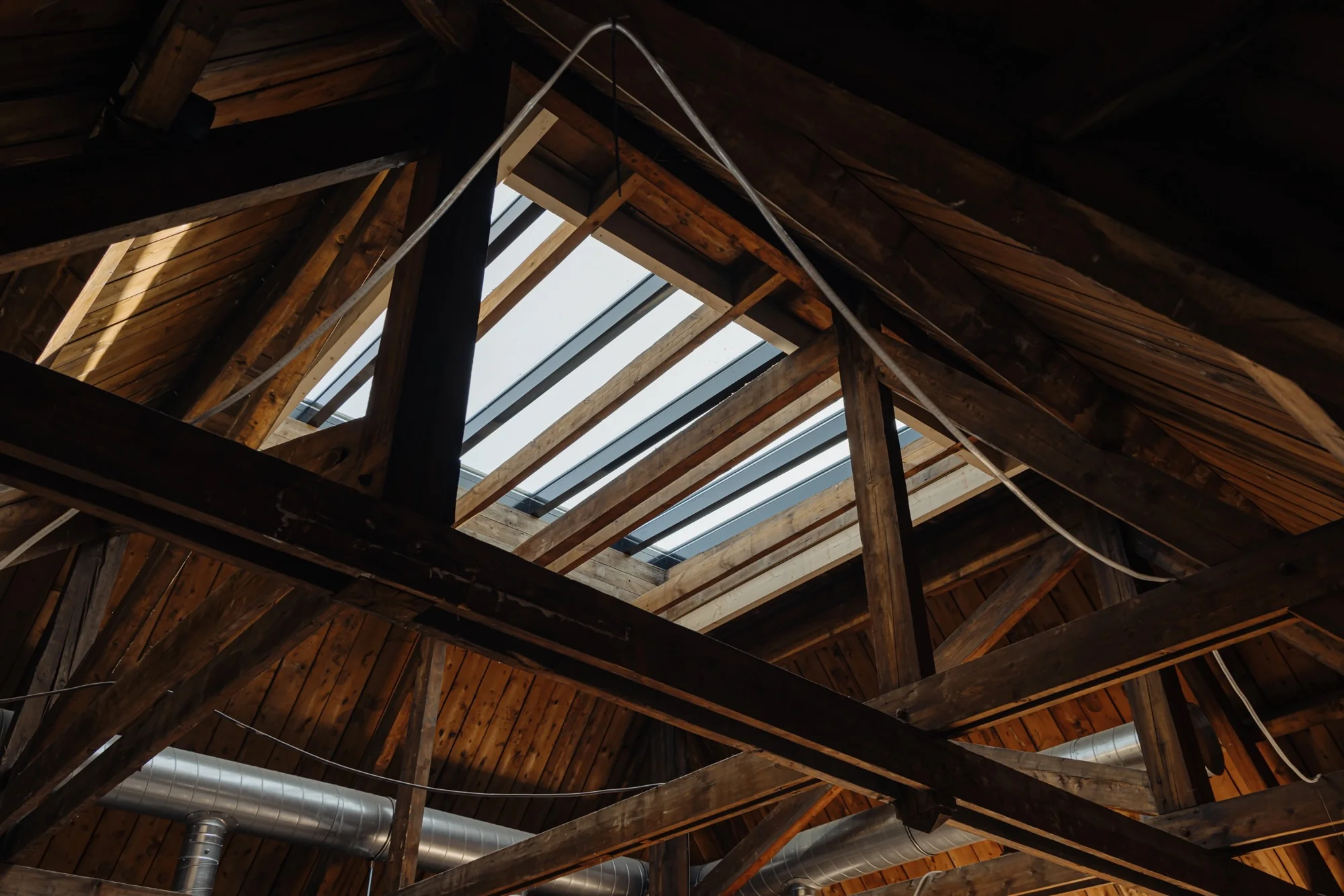 Houten dakconstructie met opengewerkte balken en dakramen aan de Leidseweg.