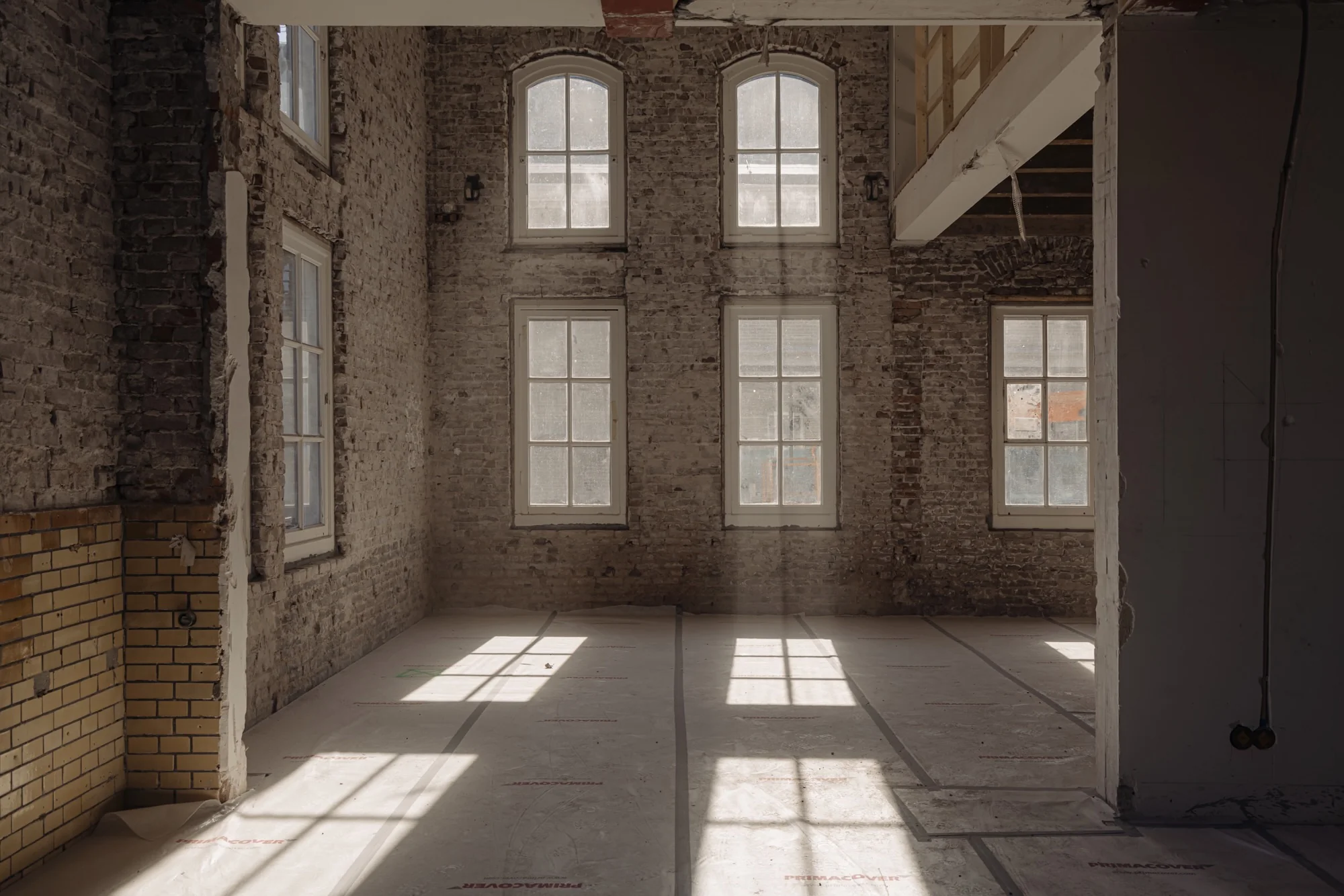 Lichtinval door hoge ramen in een casco-renovatieruimte aan de Leidseweg.