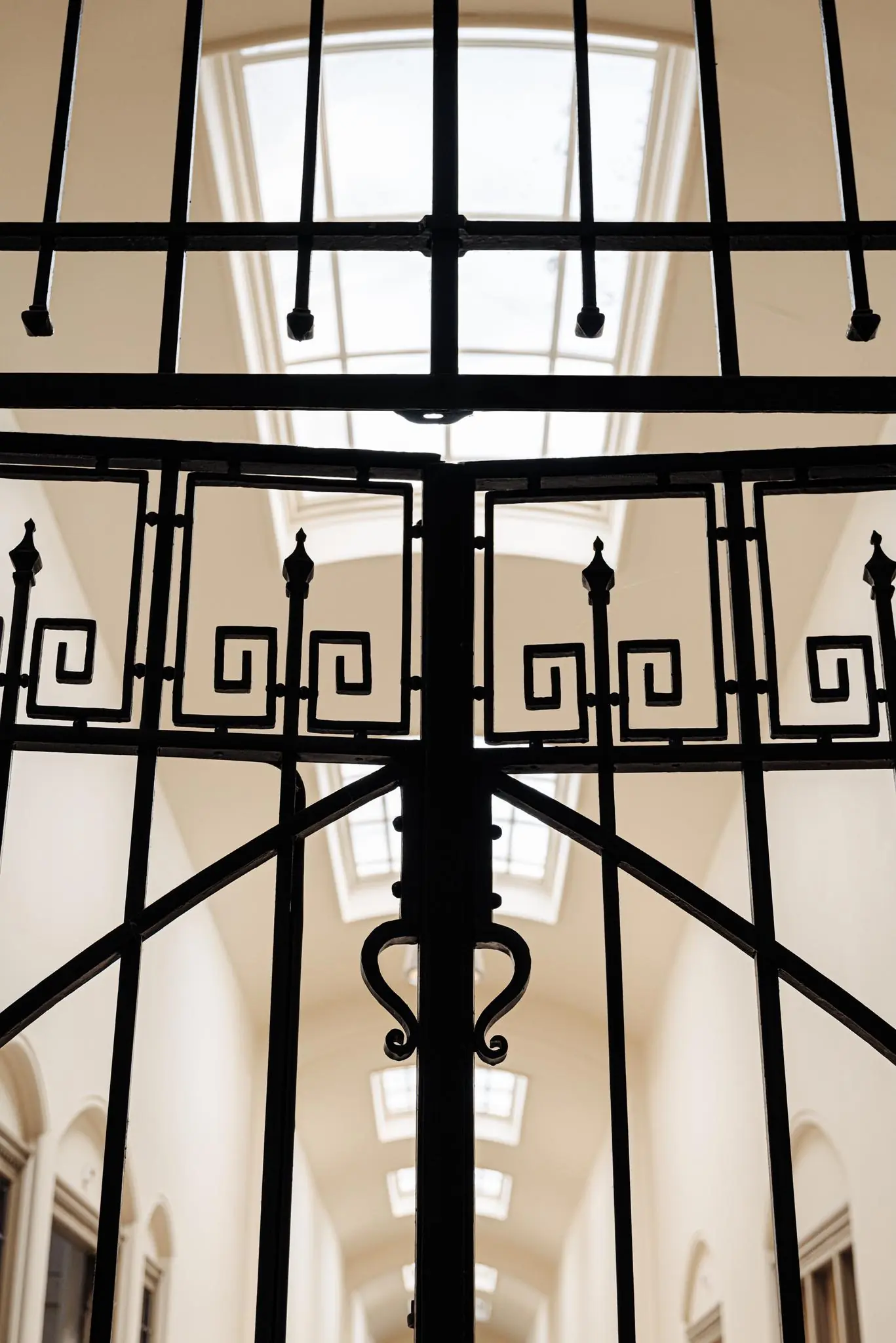 Zwart smeedijzeren hek met sierlijke patronen in een licht trappenhuis aan de Leidseweg.