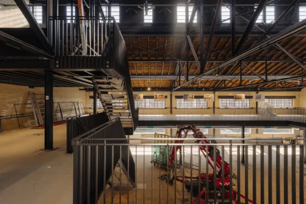 Industriële ruimte in renovatie aan de Muntkade met metalen trap, houten dakconstructie en bouwmaterieel op de begane grond.