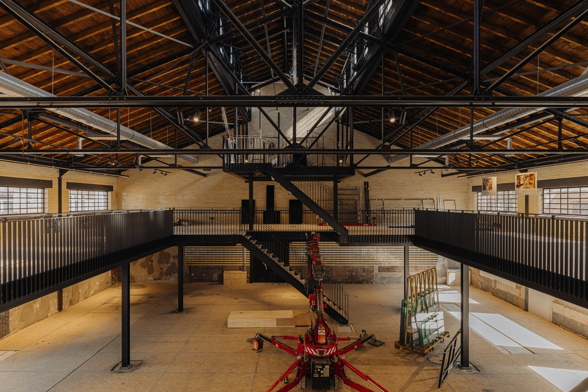 Industrieel interieur van de Muntkade met stalen constructies, houten dak en een centraal geplaatste trap.
