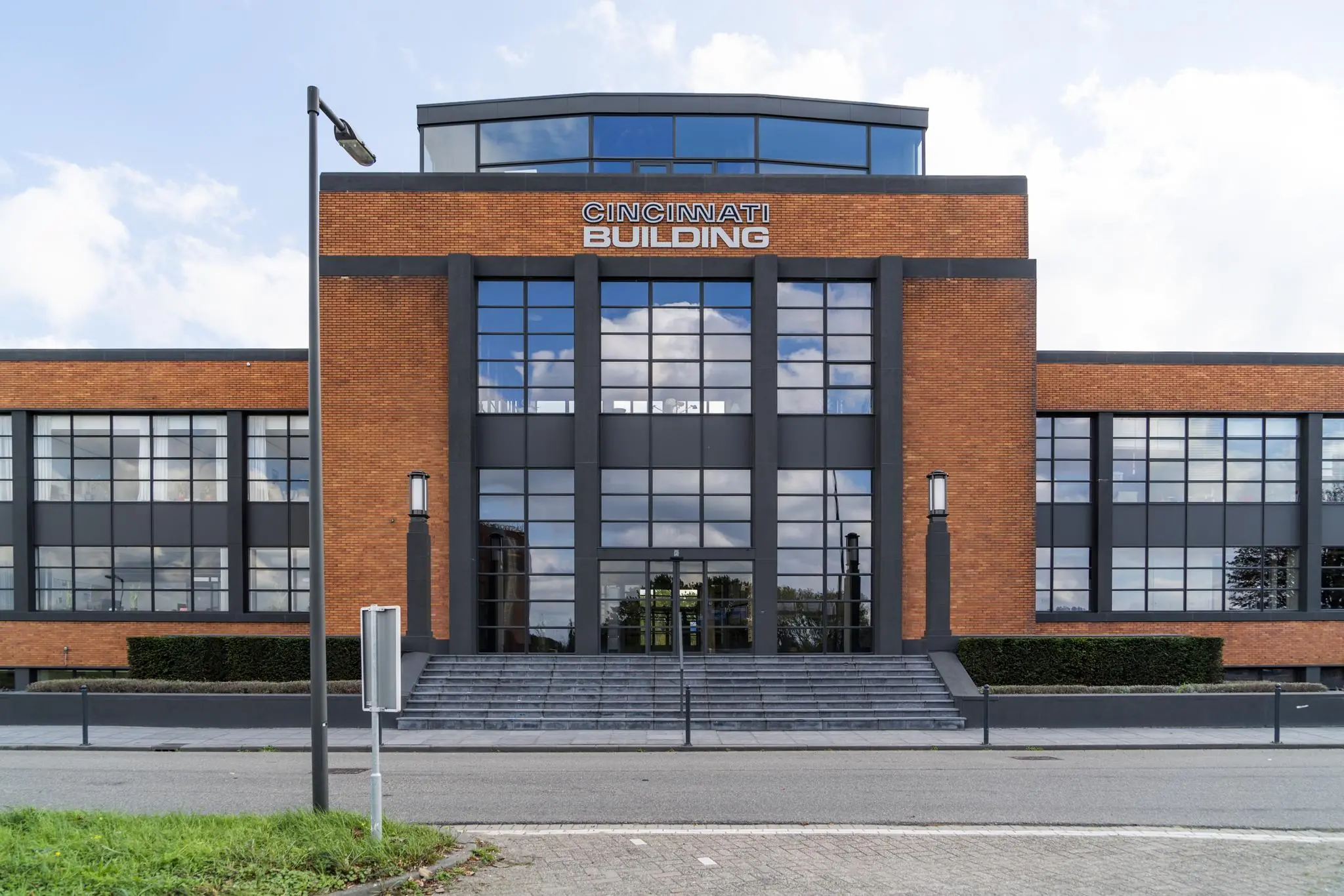 Vooraanzicht van het Cincinnati Building aan de Schiedamsedijk met een brede trap en moderne glazen gevel.