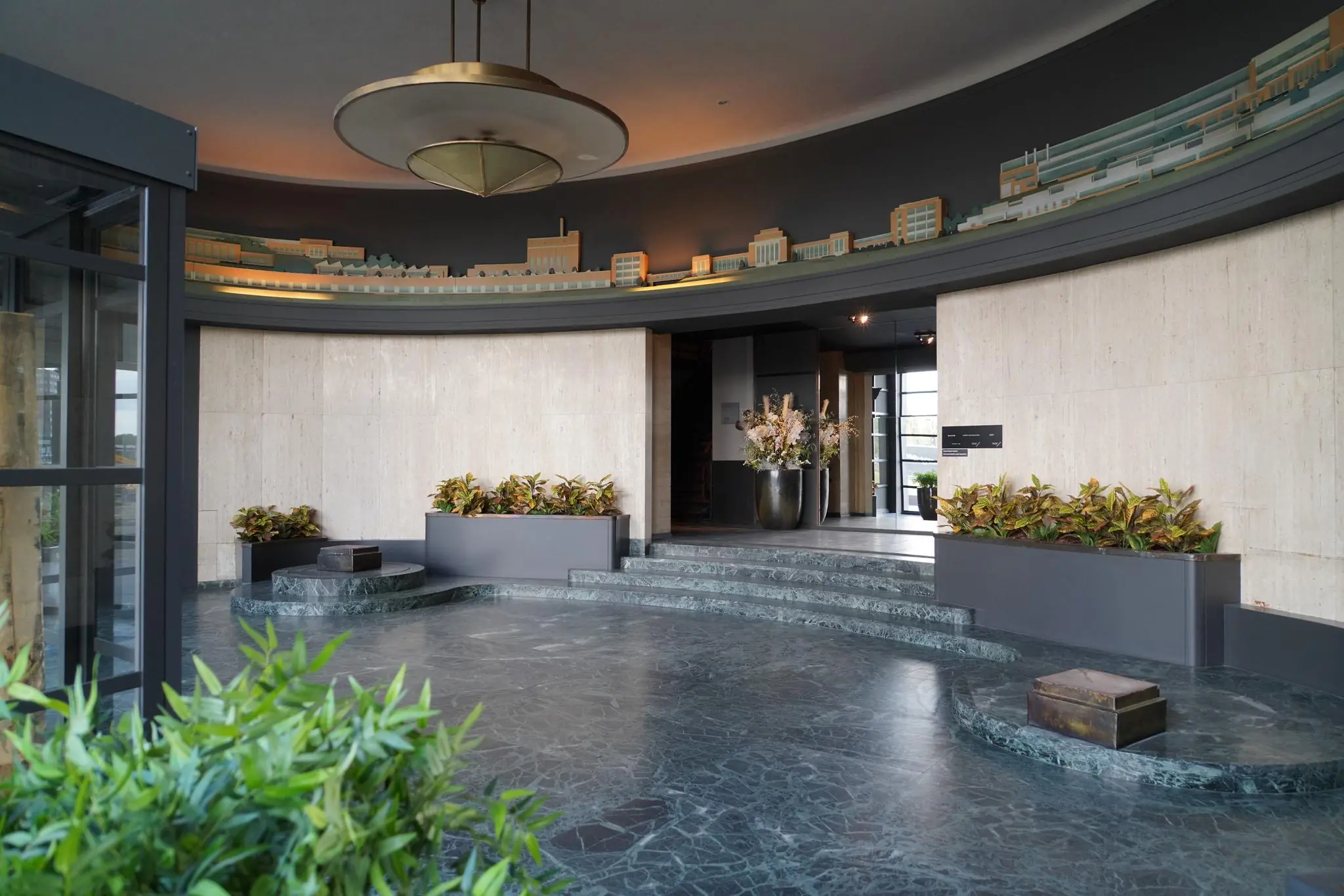 Moderne entreehal aan de Schiedamsedijk met marmeren vloer, plantenbakken en een reliëf van de skyline op de muur.