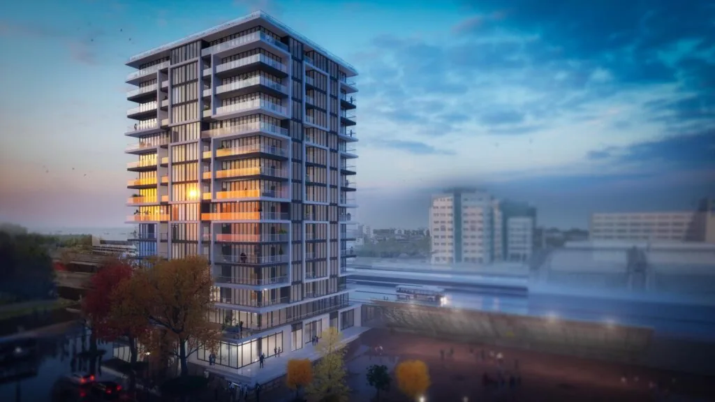 Moderne woontoren aan het Stationsplein bij zonsondergang met uitzicht op een treinstation en stadsgebouwen.