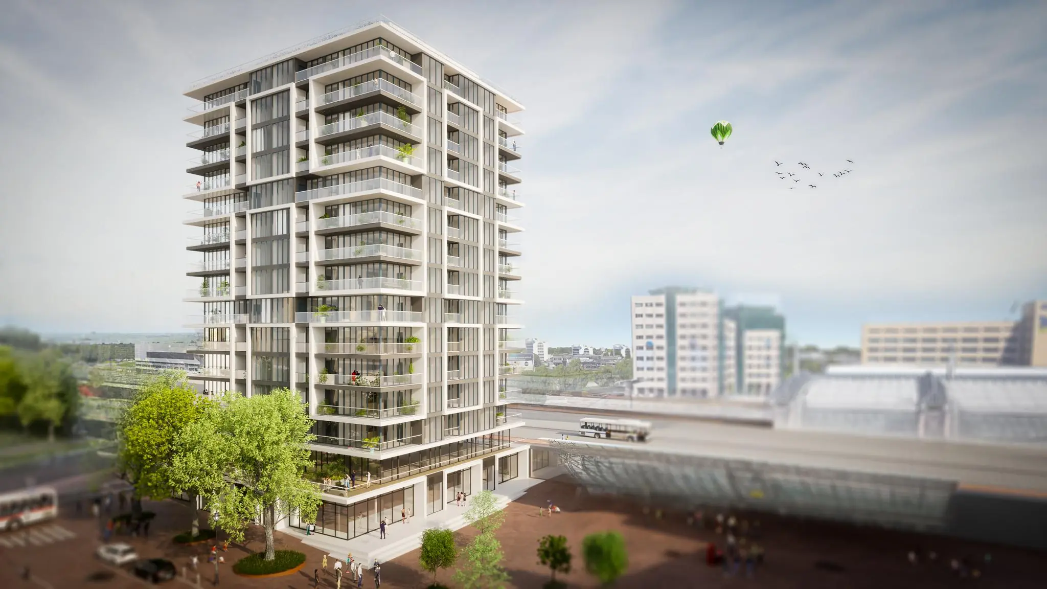 Moderne woontoren aan het Stationsplein met glazen balkons en uitzicht op een treinstation.