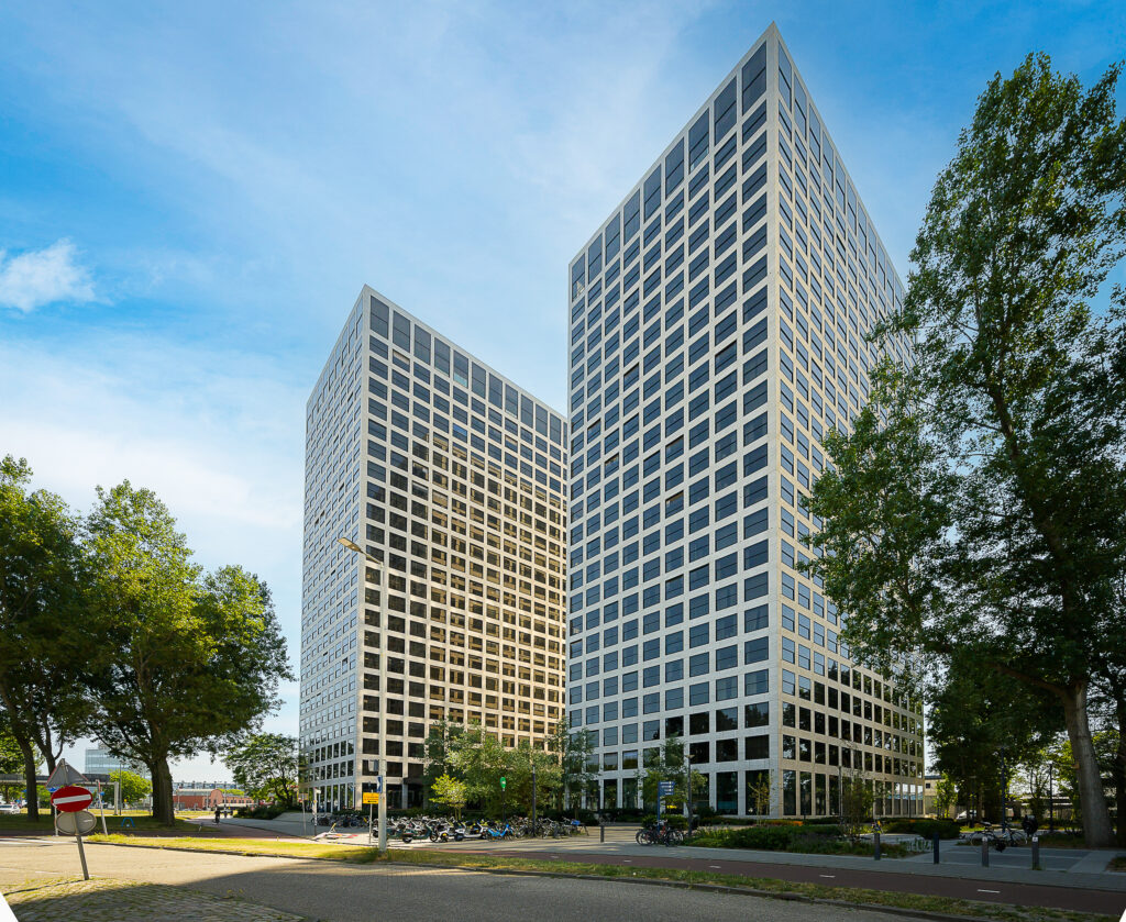 Twee moderne kantoortorens aan de Galvanistraat met een gevel van rechthoekige ramen, omringd door bomen en fietsen.