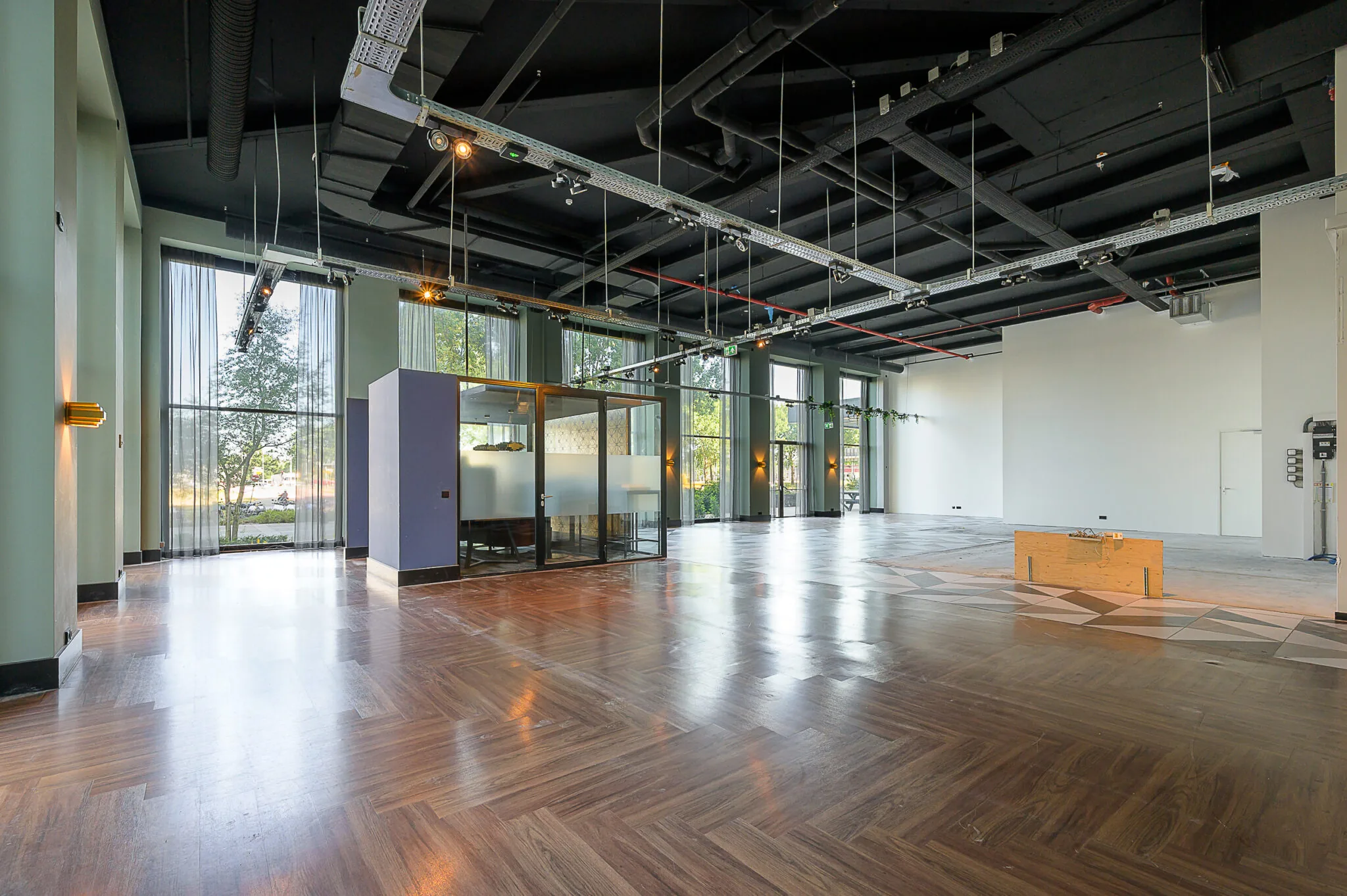 Ruime, moderne kantoorruimte aan de Galvanistraat met hoge plafonds, grote ramen en een glazen vergaderruimte.