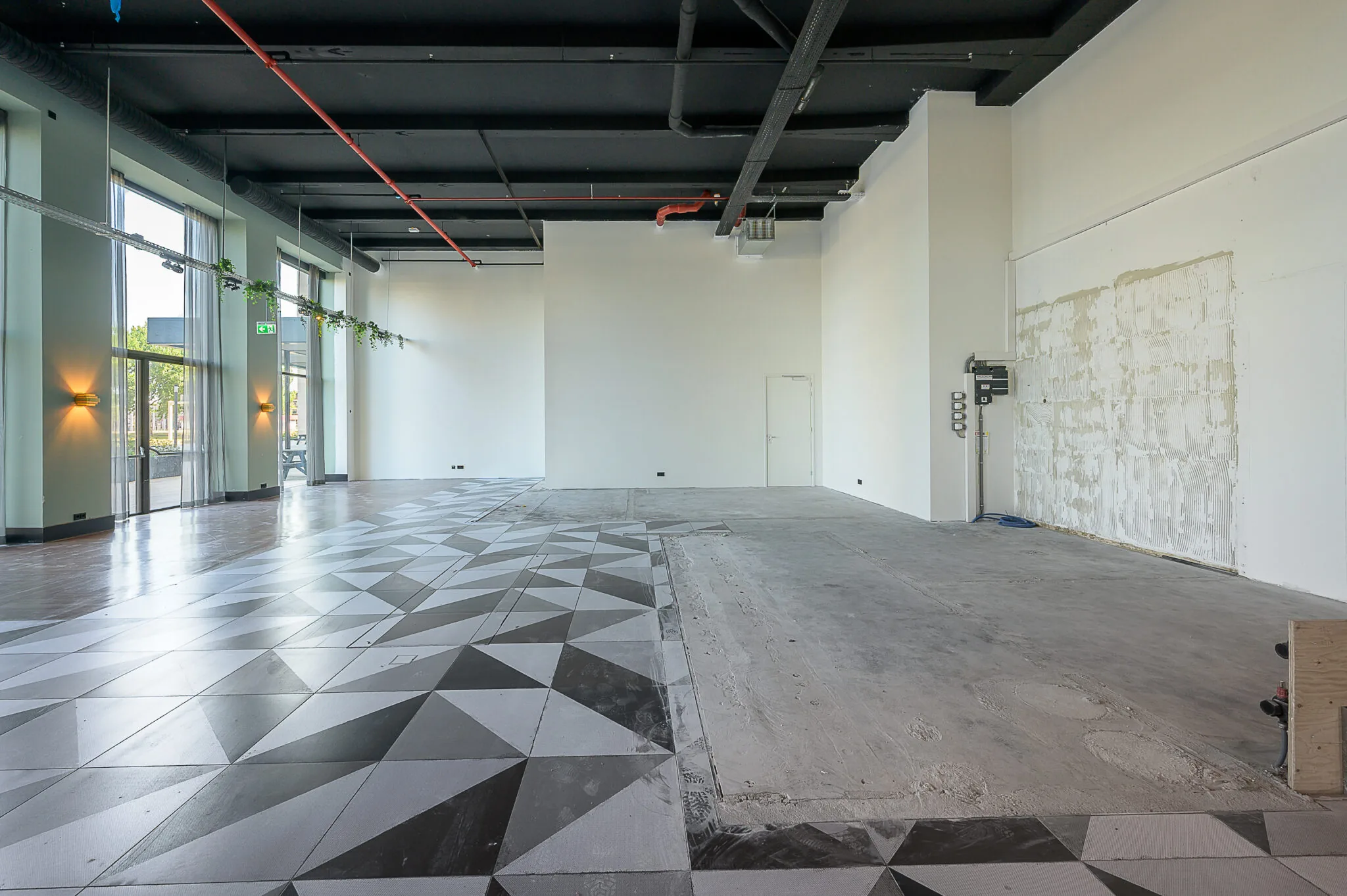 Leegstaand en deels gerenoveerd winkel- of bedrijfsruimte aan de Galvanistraat met modern geometrisch tegelpatroon op de vloer.