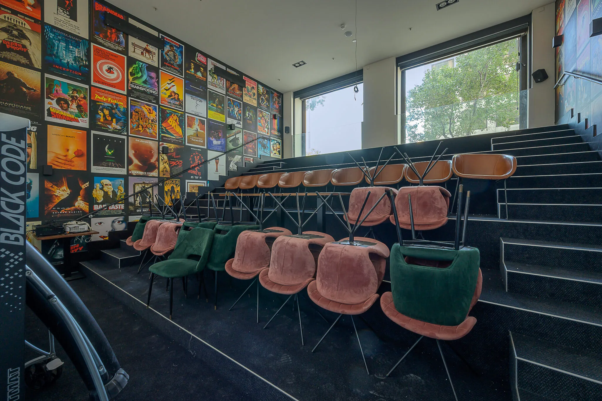 Kleine bioscoopzaal aan de Galvanistraat met opgestapelde stoelen en een wand vol filmklassieker-posters.