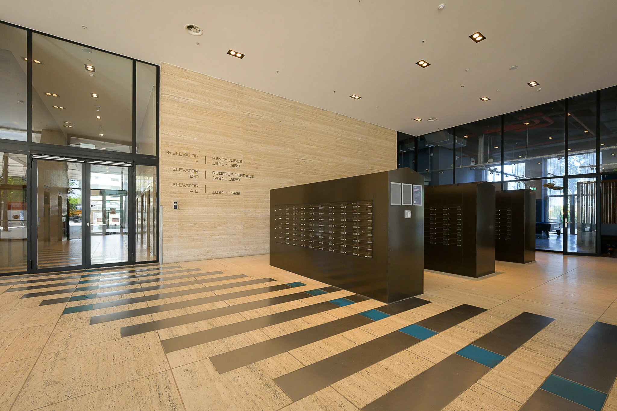 Moderne entreehal aan de Galvanistraat met brievenbussen, glazen deuren en liftinformatie op de muur.