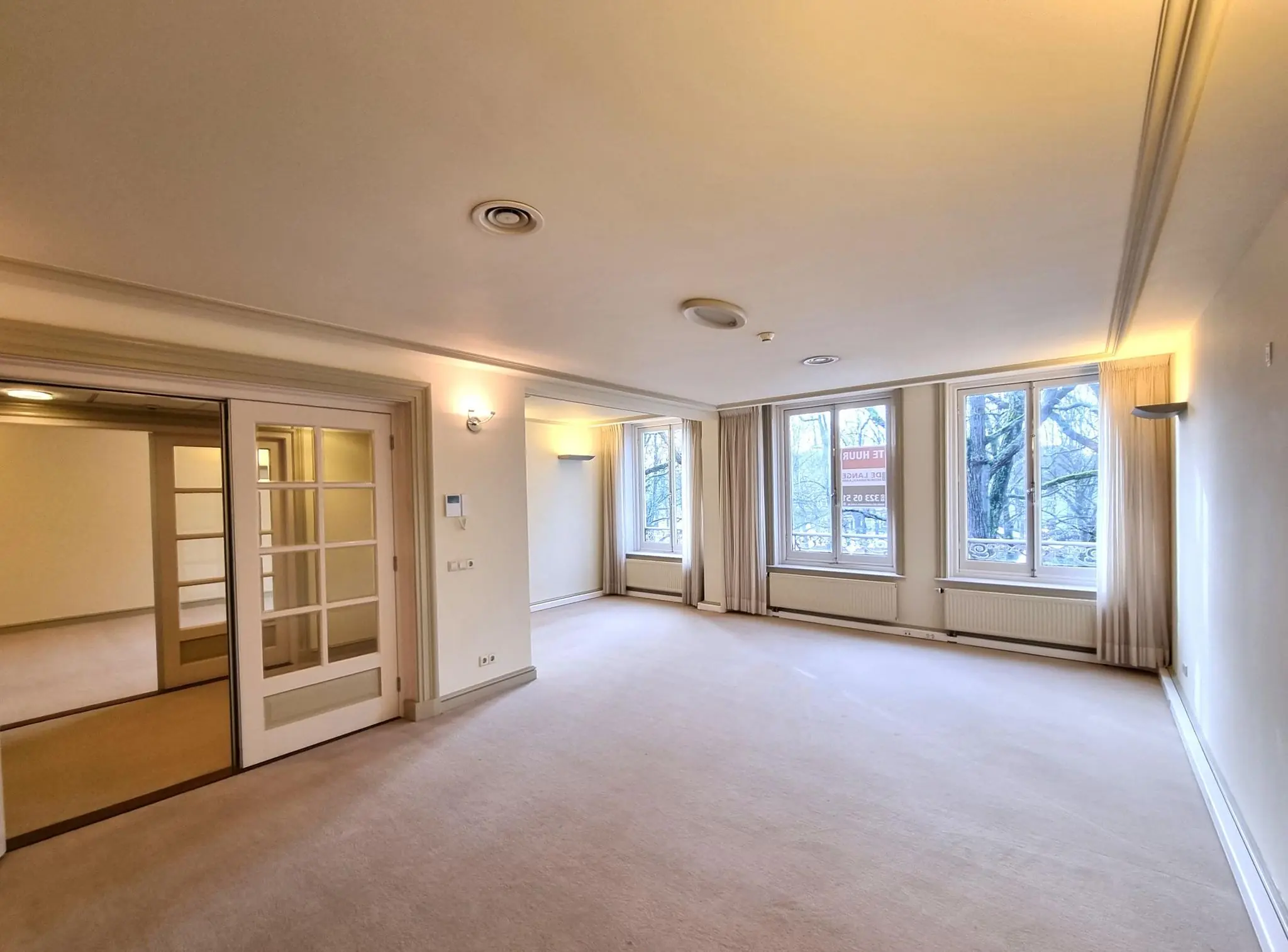 Ruime, lichte woonkamer met grote ramen en uitzicht op het Lange Voorhout.