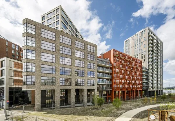 Moderne woongebouwen aan de Hellingbaan met diverse gevelmaterialen en balkons, onder een deels bewolkte hemel.