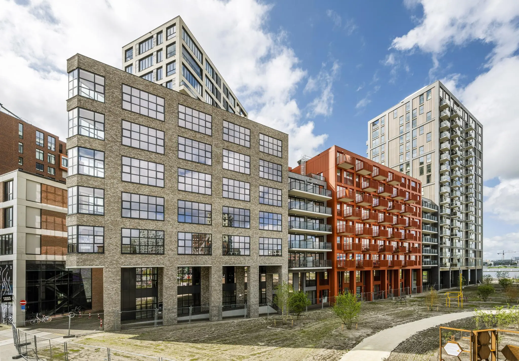 Moderne woongebouwen aan de Hellingbaan met diverse gevelmaterialen en balkons, onder een deels bewolkte hemel.