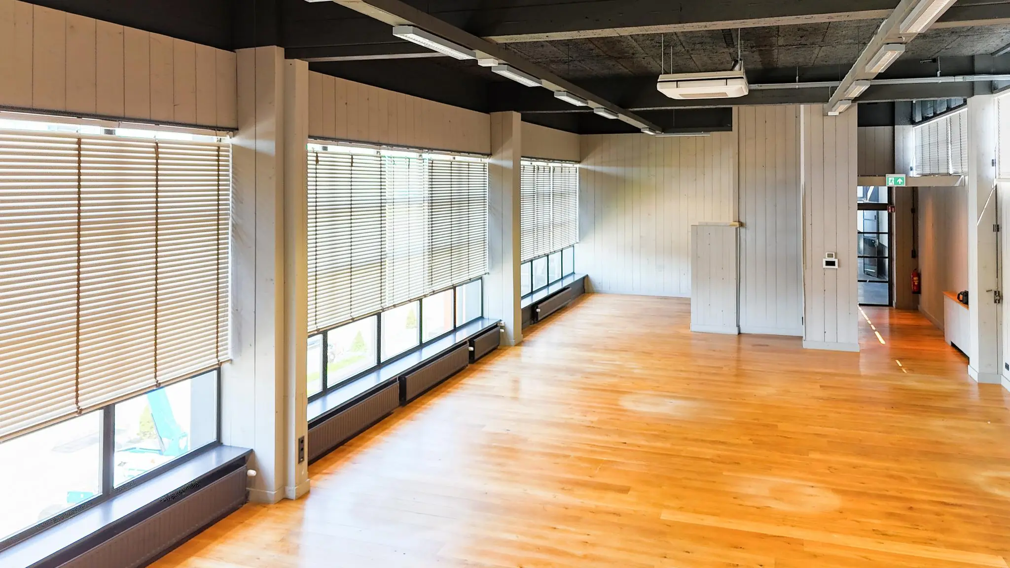 Lichte, lege kantoorruimte aan de Schiedamsedijk met houten vloer, grote ramen en lamellen.