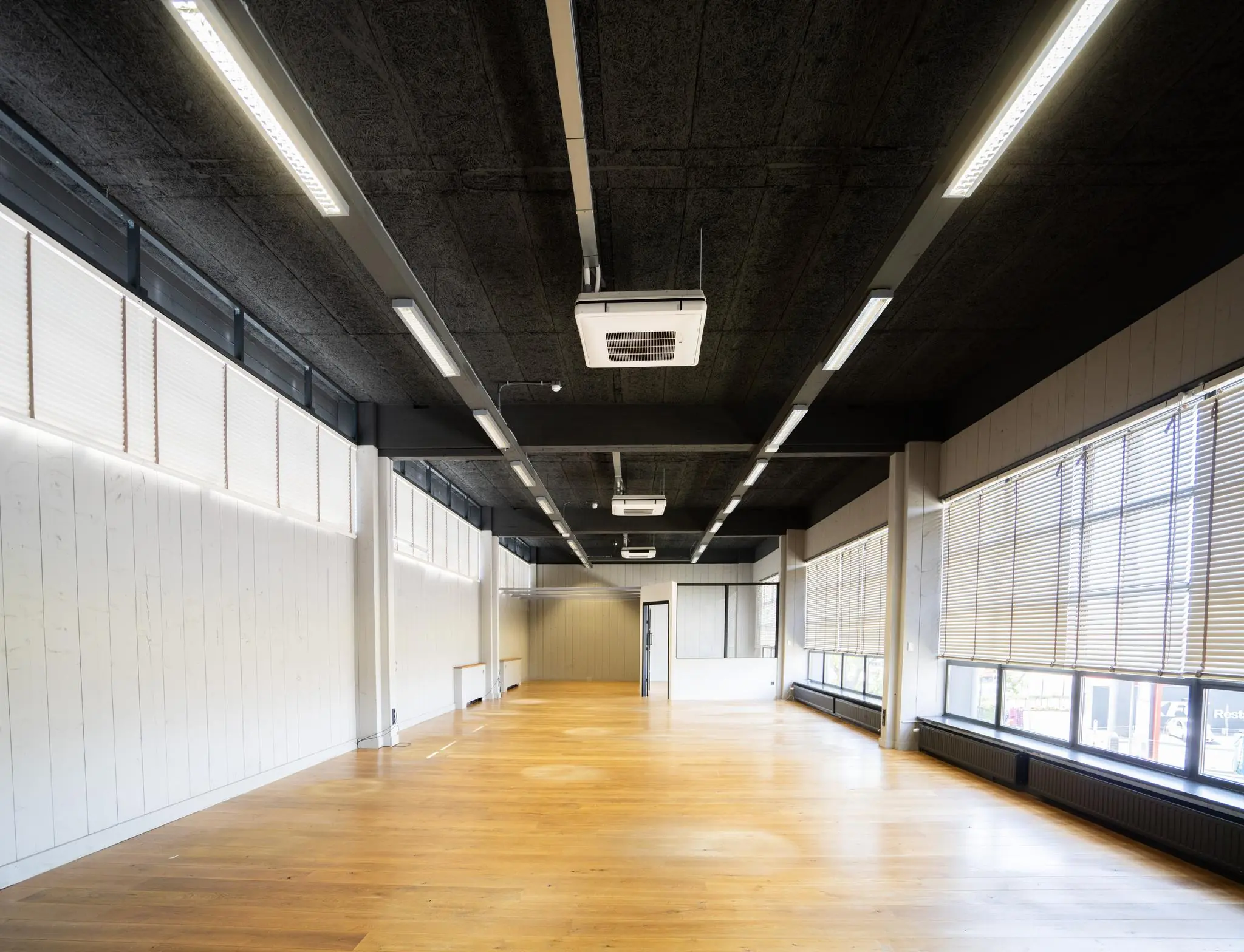 Lichte, ruime kantoorruimte aan de Schiedamsedijk met houten vloer, grote ramen en systeemplafondverlichting.