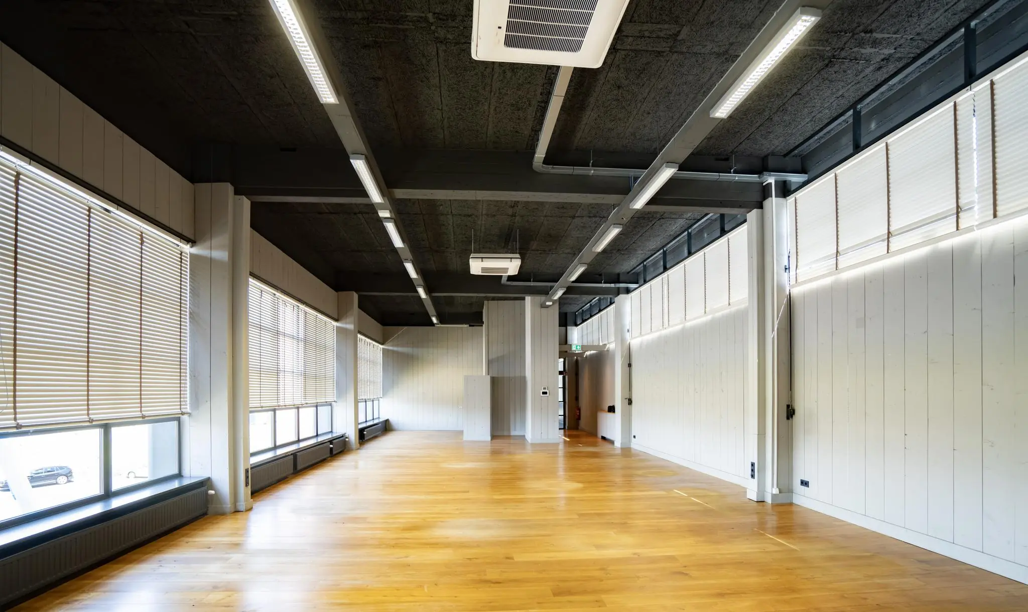 Lichte, leegstaande kantoorruimte aan de Schiedamsedijk met houten vloer, grote ramen en moderne plafondverlichting.