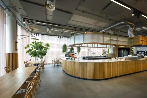 Modern interieur van een horecagelegenheid aan de Moermanskade met een ronde houten bar, hoge plafonds en veel natuurlijk licht.