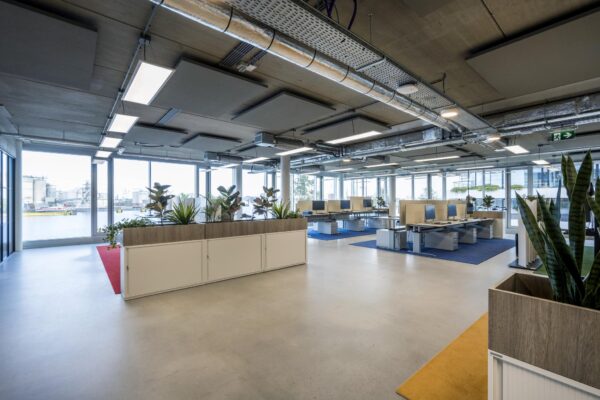 Moderne open kantoorruimte aan de Moermanskkade met werkplekken, planten en uitzicht op het water.