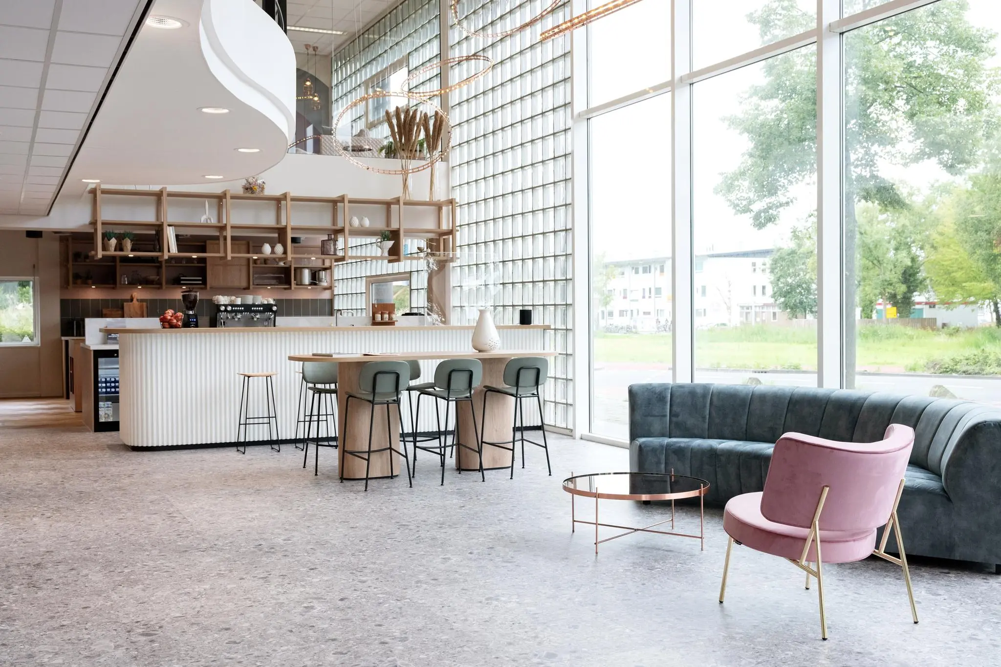 Moderne en lichte lounge- en koffiehoek in een interieur aan de Overschiestraat met grote ramen en stijlvol meubilair.