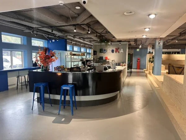 Moderne, kleurrijke koffieruimte met een zwarte bar en de tekst "EUREKA" aan de muur in een bedrijfsruimte aan de Daltonlaan.