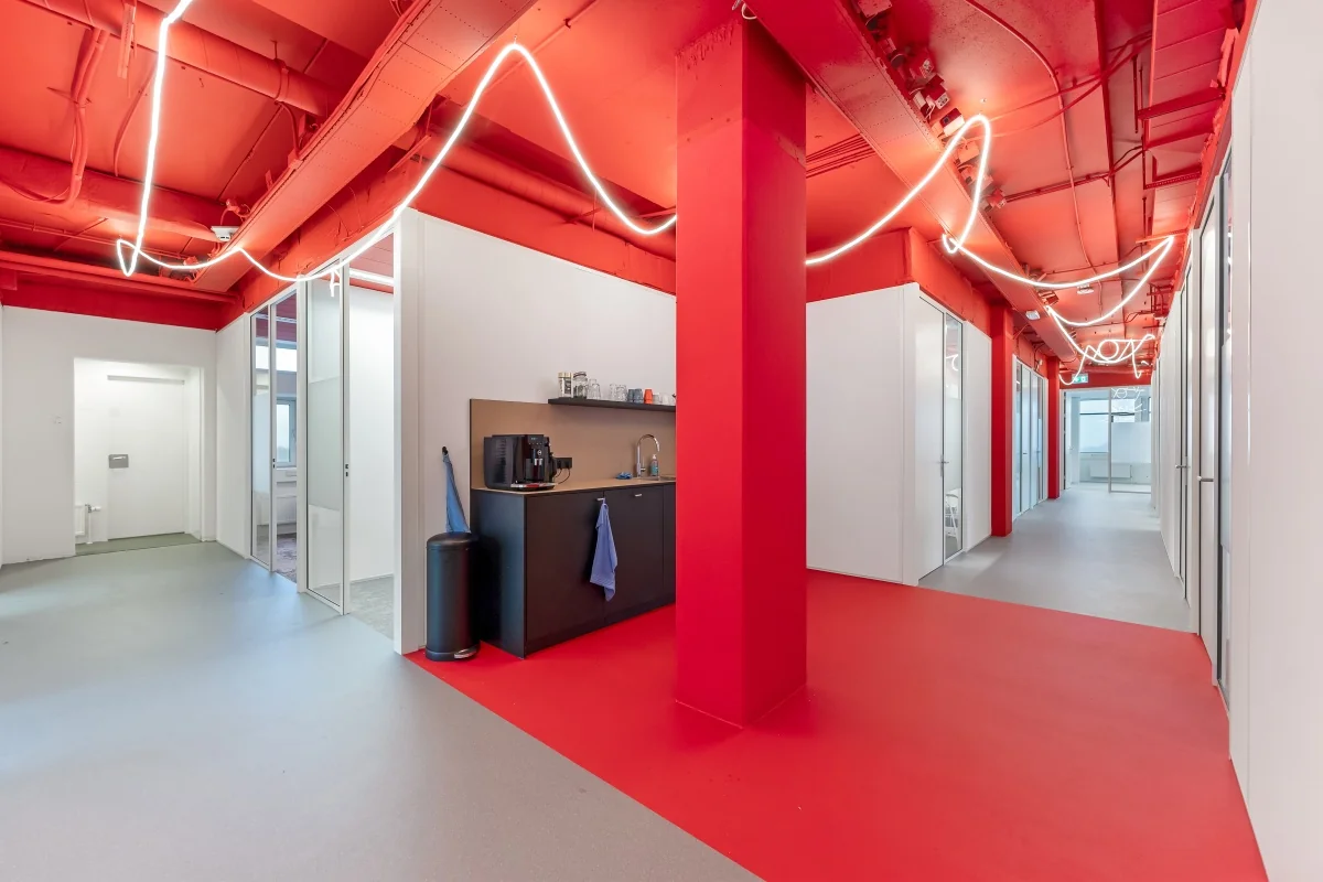 Modern kantoorinterieur aan de Daltonlaan met felrode accenten, LED-verlichting en een koffiehoek.