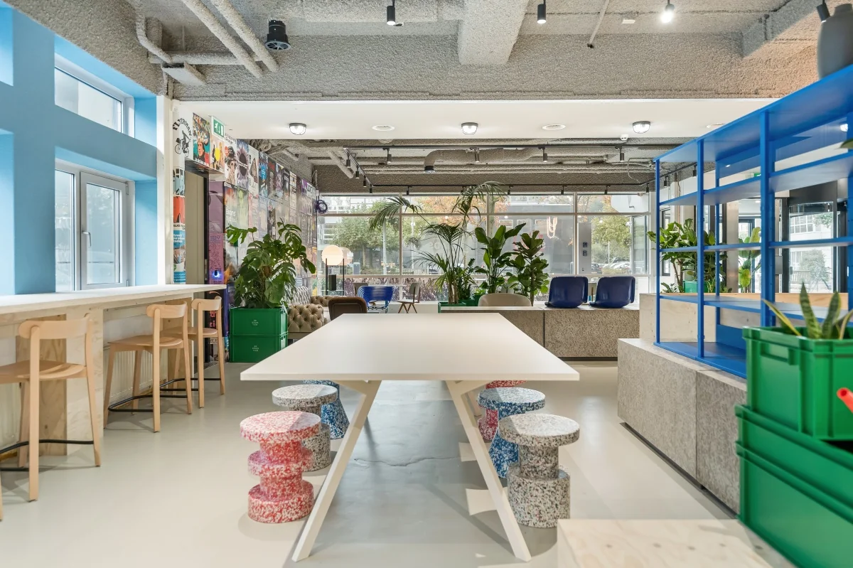 Moderne kantoorruimte aan de Daltonlaan met kleurrijke zitplekken, veel planten en een creatieve inrichting.