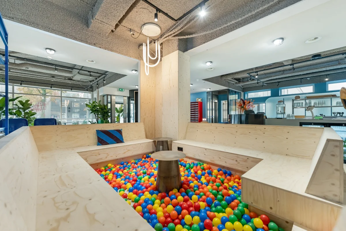 Moderne zithoek met houten banken rondom een ballenbak in een creatieve kantoorruimte aan de Daltonlaan.
