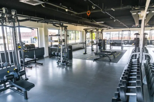 Moderne en ruime fitnessruimte met diverse krachttrainingsapparaten, gewichten en functionele trainingszones.