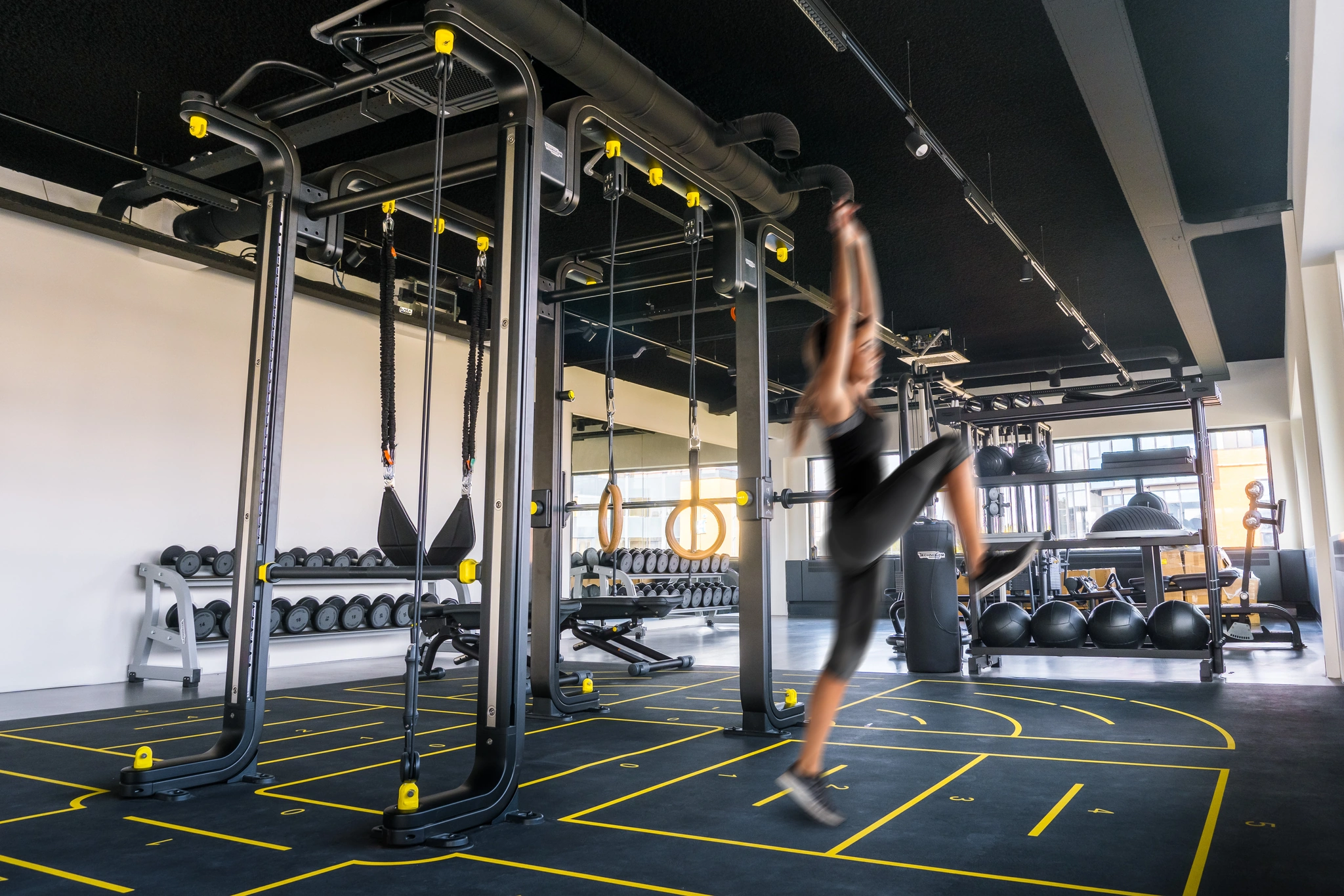 Vrouw traint in een moderne sportschool met functionele trainingsrekken en fitnessapparatuur.