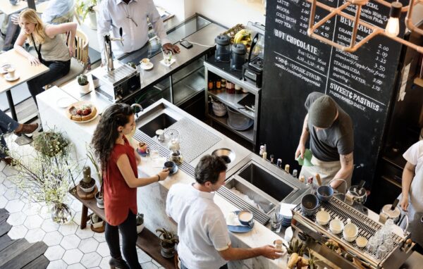 Drukbezochte koffiebar met barista’s achter de toonbank en klanten die wachten op hun bestellingen.
