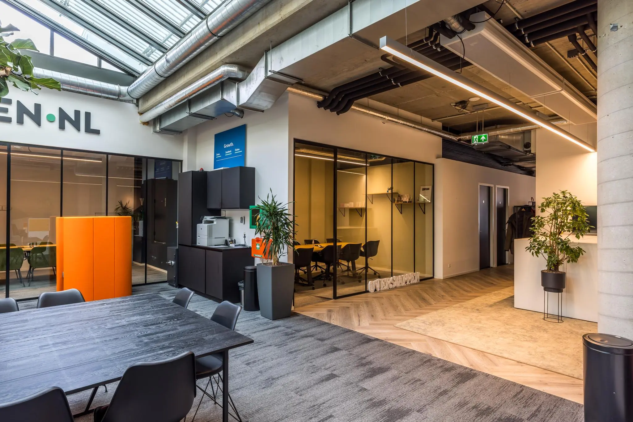 Moderne kantoorruimte aan de Overtoom met vergaderruimtes, zithoek en veel daglicht door het glazen dak.