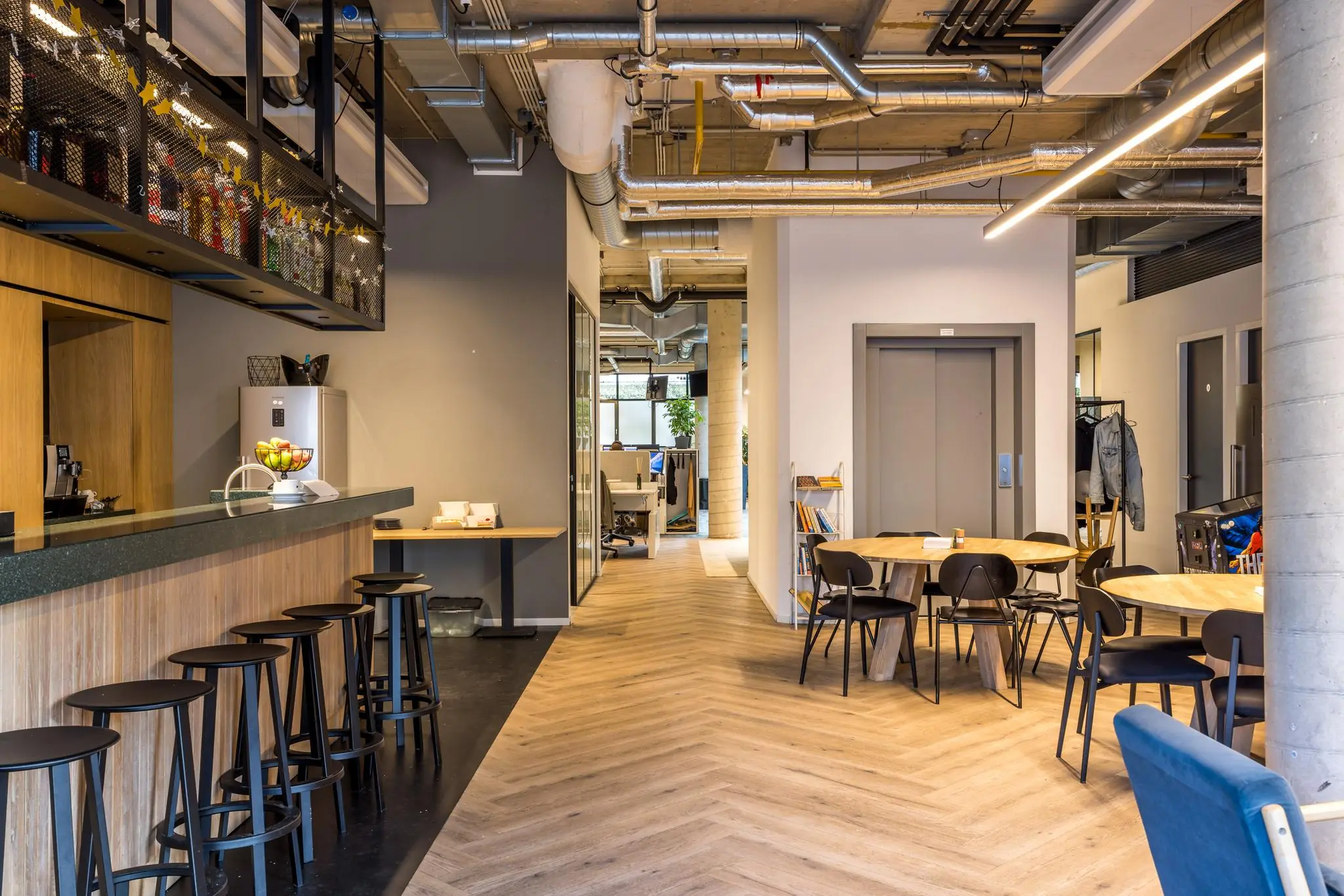 Modern ingerichte kantoorruimte aan de Overtoom met een bar, zitgedeelte en zicht op werkplekken.