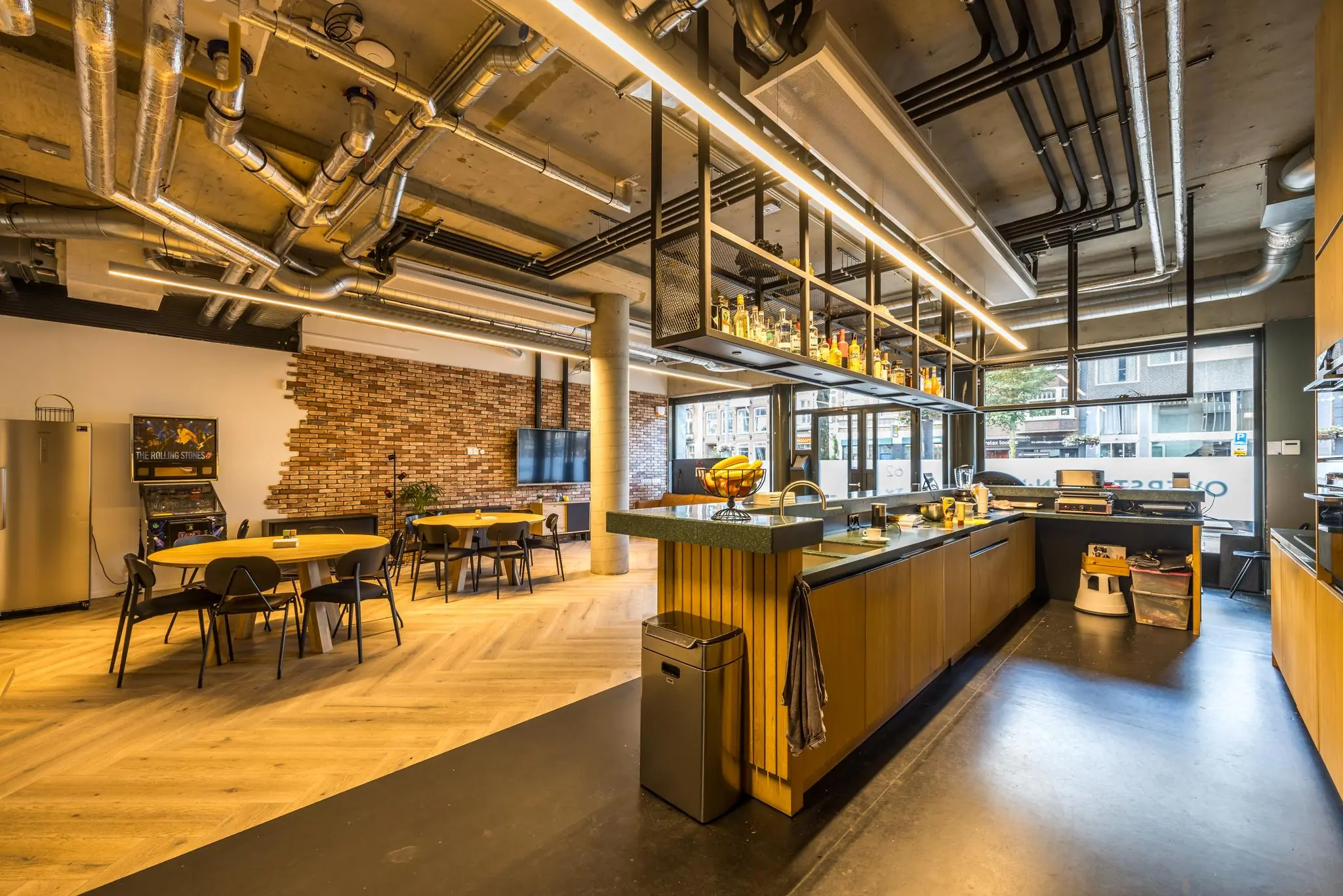 Moderne kantoorruimte aan de Overtoom met open keuken, zitgedeelte en industriële plafondafwerking.