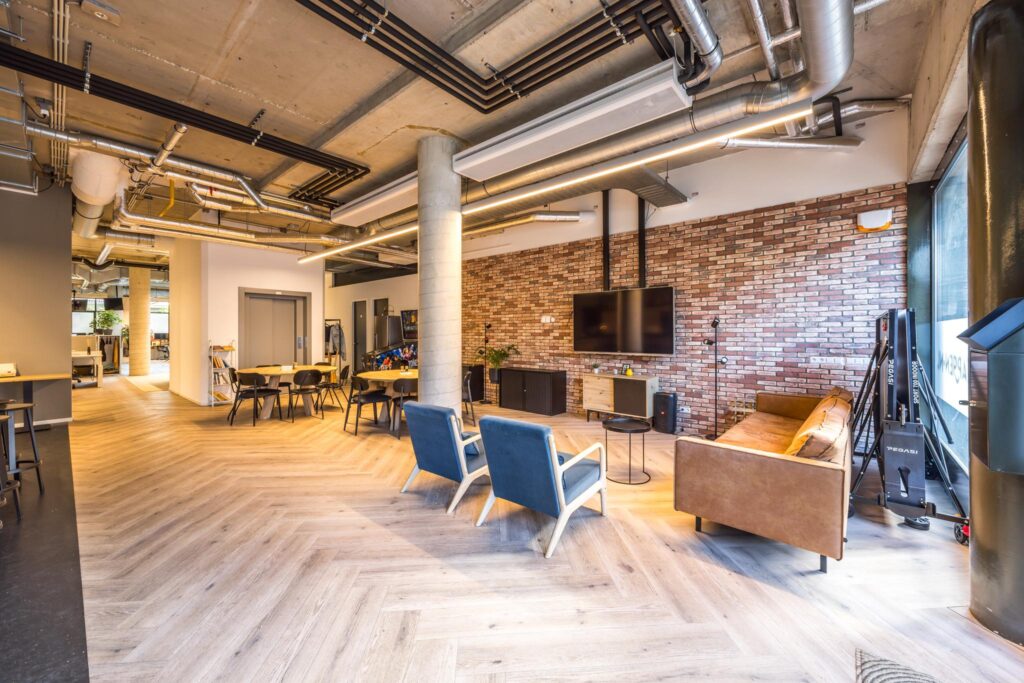 Moderne, industrieel ingerichte kantoorruimte aan de Overtoom met zithoek, vergadertafels en zichtbare plafondleidingen.