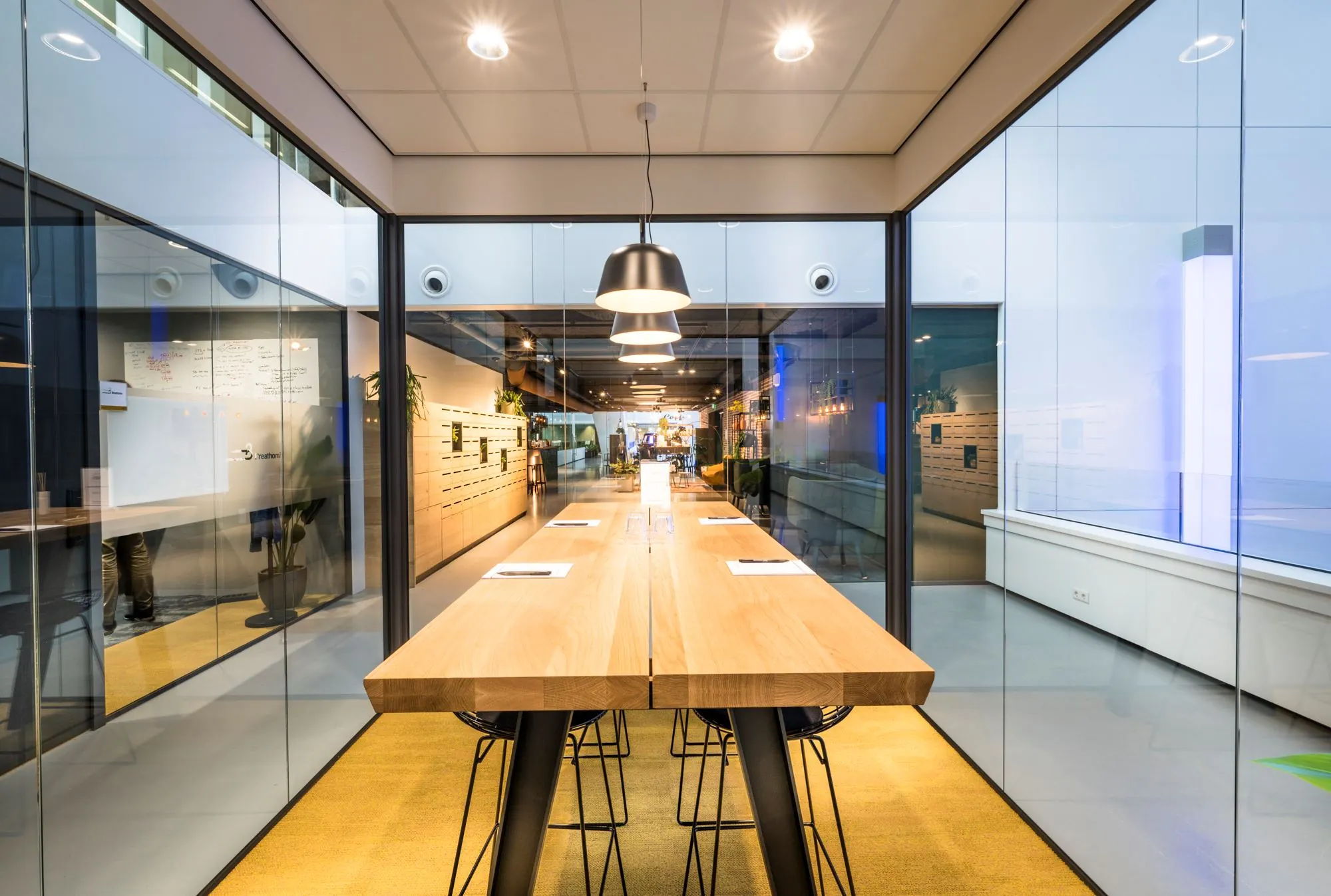 Moderne vergaderruimte met glazen wanden, een lange houten tafel en hangende lampen in kantoor 237_2160.