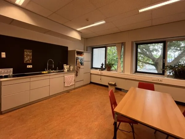 Kantine met keukenblok, tafel en uitzicht op bomen aan de 2e Daalsedijk.