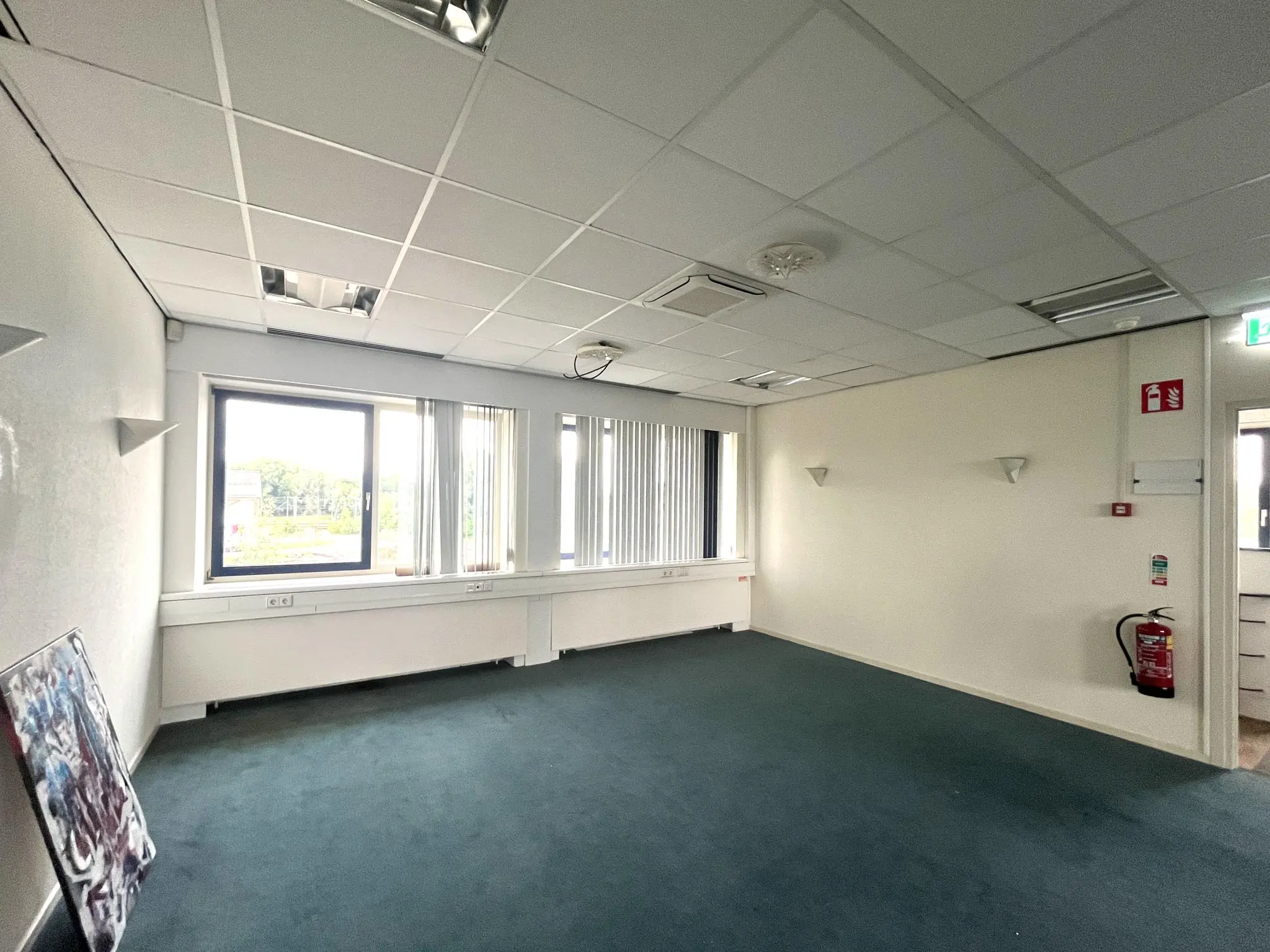 Leeg kantoorruimte met tapijtvloer, systeemplafond en grote ramen aan de 2e Daalsedijk.