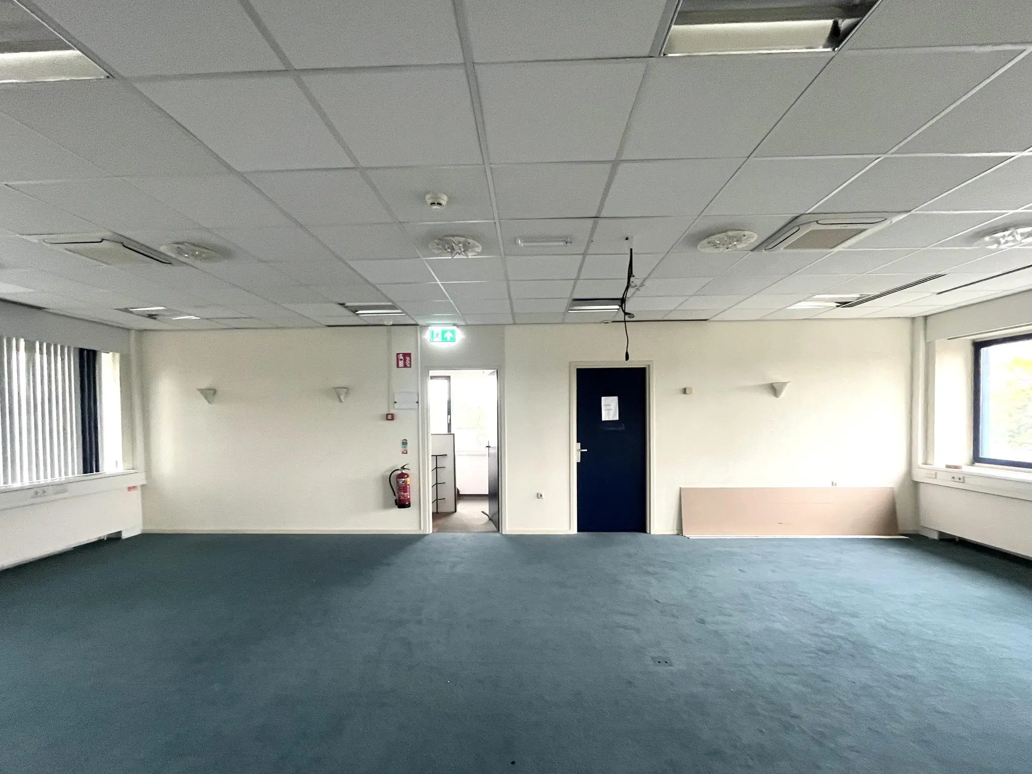 Leegstaand kantoor met blauw tapijt en systeemplafond aan de 2e Daalsedijk.