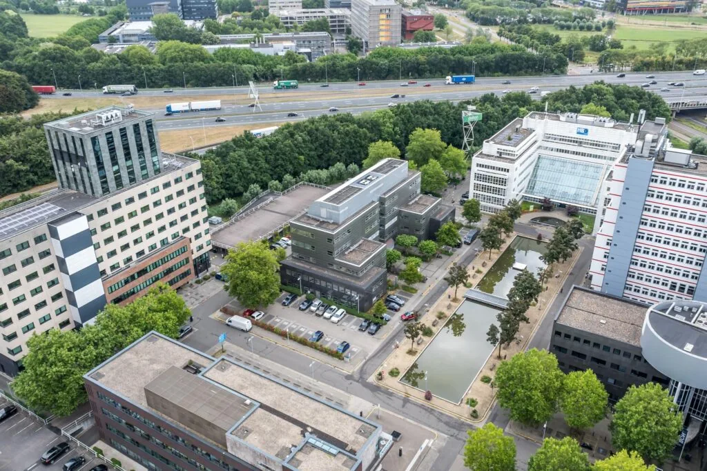 Luchtfoto van kantorencomplex aan de Daltonlaan in Utrecht met omliggende gebouwen, vijvers en snelweg op de achtergrond.