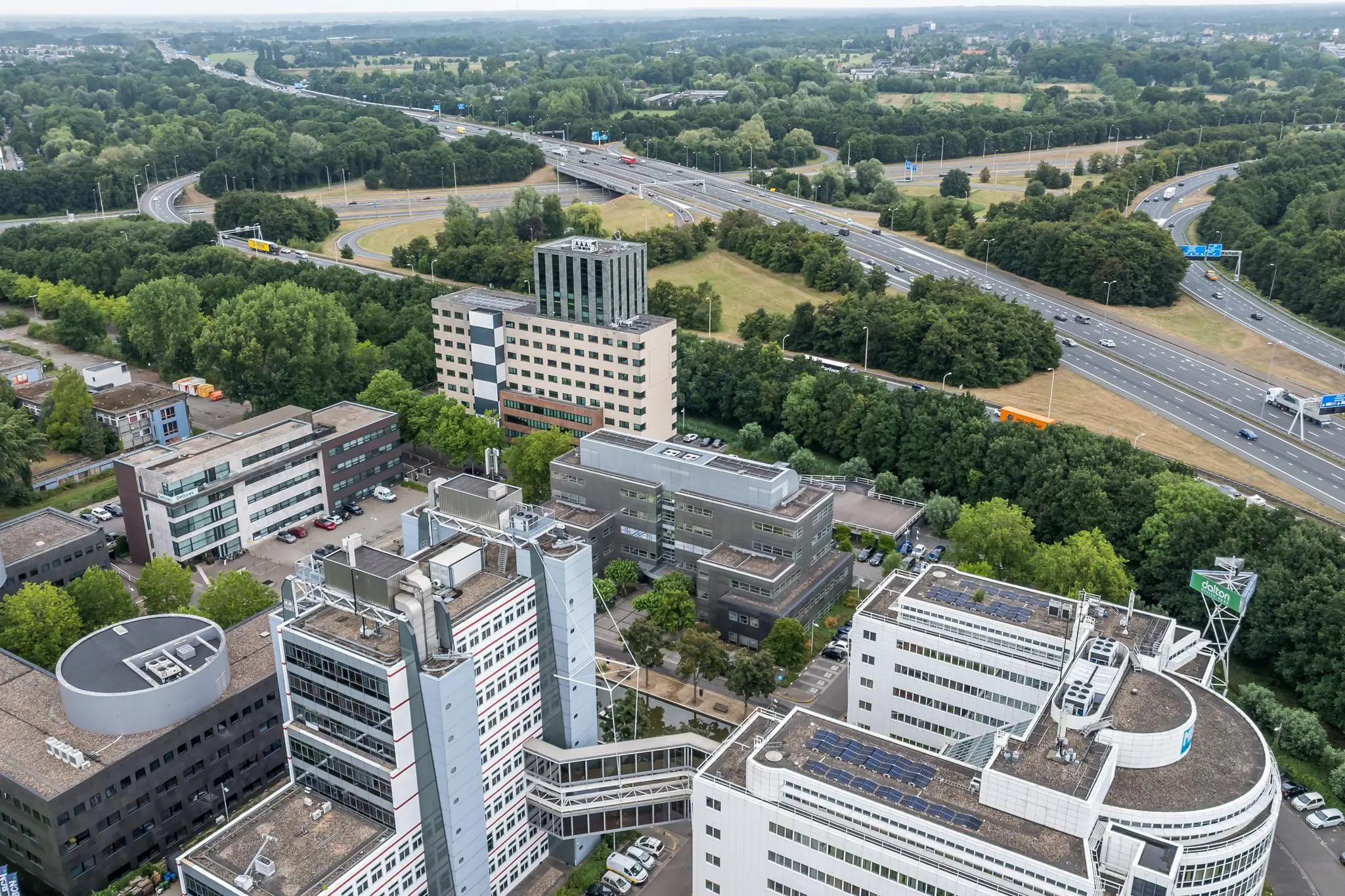 Luchtfoto van kantoorgebouwen aan de Daltonlaan in Utrecht, omgeven door snelwegen en groen.