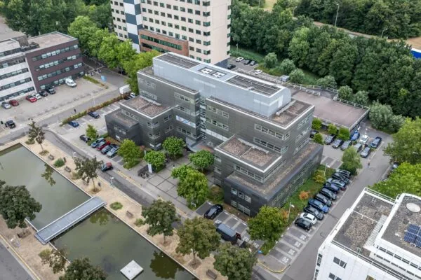 Luchtfoto van een modern kantoorgebouw aan de Daltonlaan in Utrecht, omringd door parkeerplaatsen, groen en een vijver.