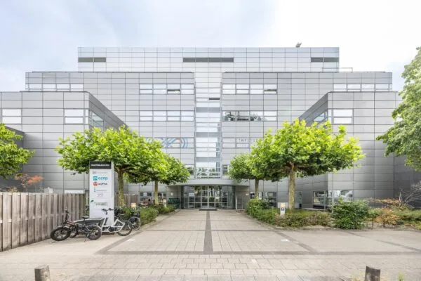 Ingang van een modern kantoorgebouw aan de Daltonlaan 400 in Utrecht, omgeven door jonge bomen en fietsenrekken.