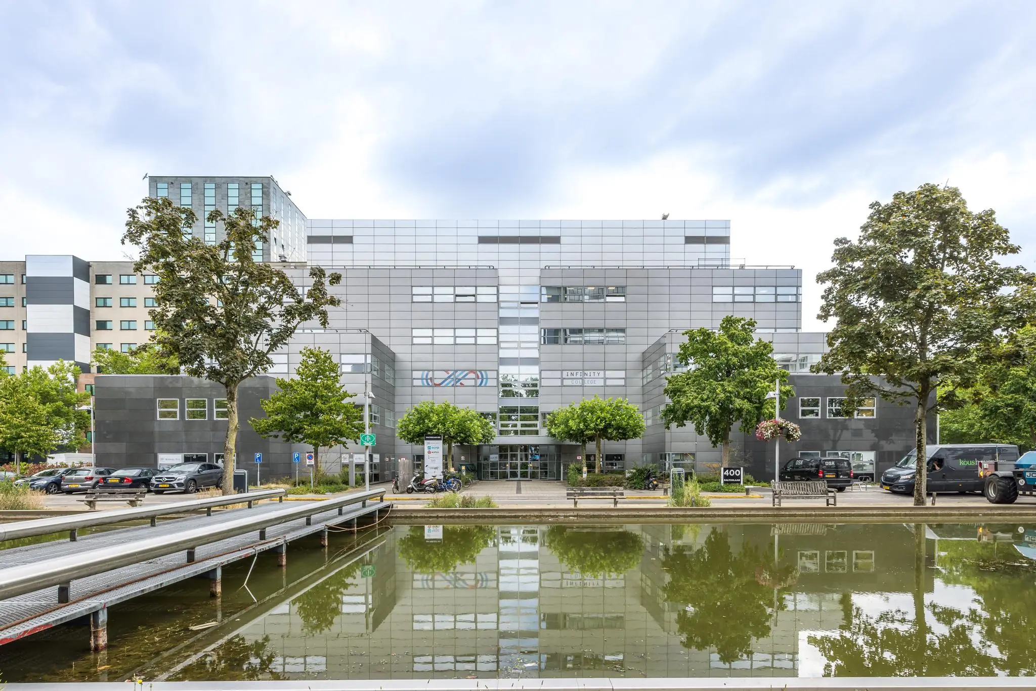 Modern kantoorgebouw aan de Daltonlaan in Utrecht met vijver en brug op de voorgrond.